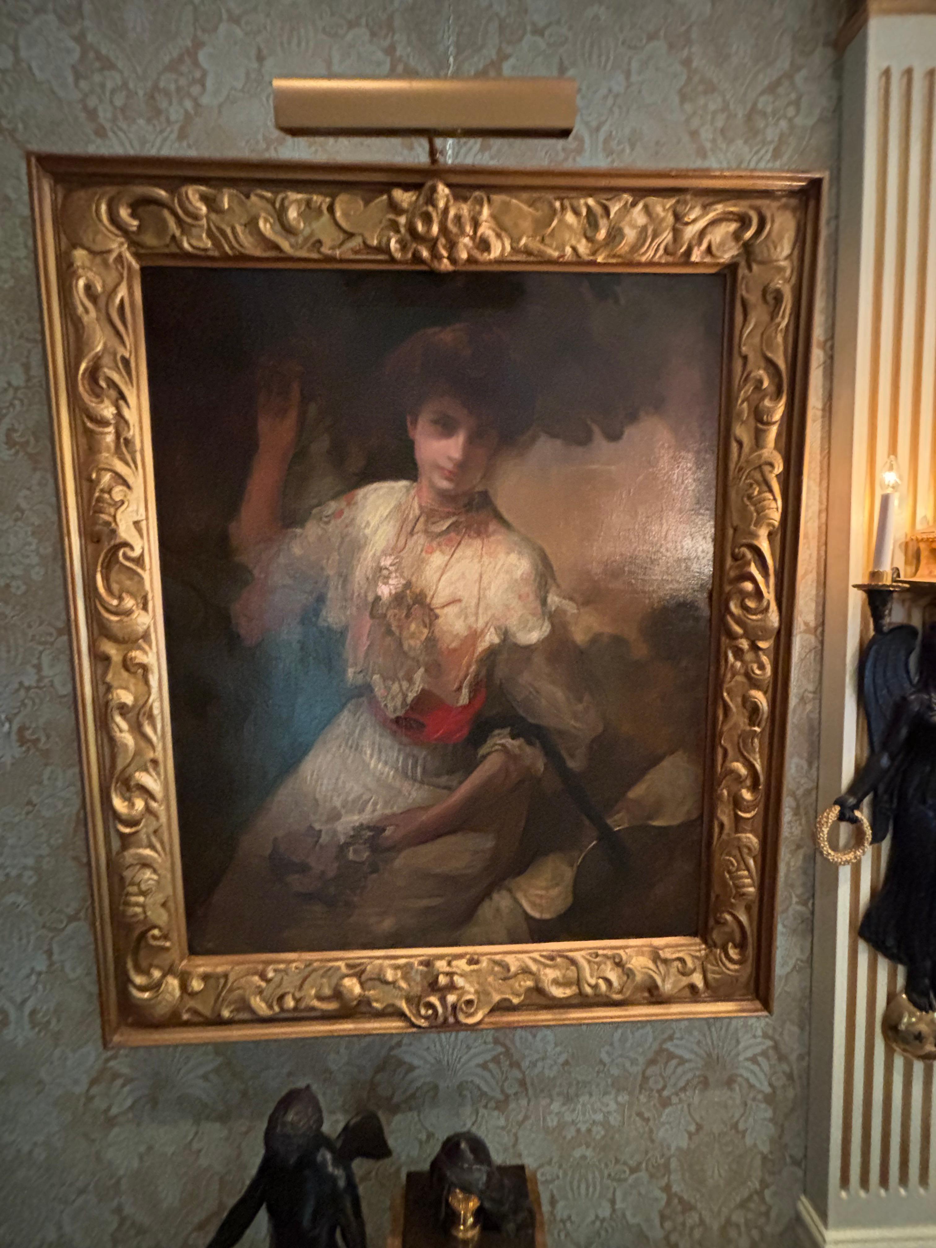 Un grande e bellissimo ritratto di una signora seduta con il cappello su un braccio che tiene un bouquet di fiori, mentre l'altro braccio è rivolto verso l'alto e tiene un ramo di un albero. Questo olio su tela originale è opera dell'artista
