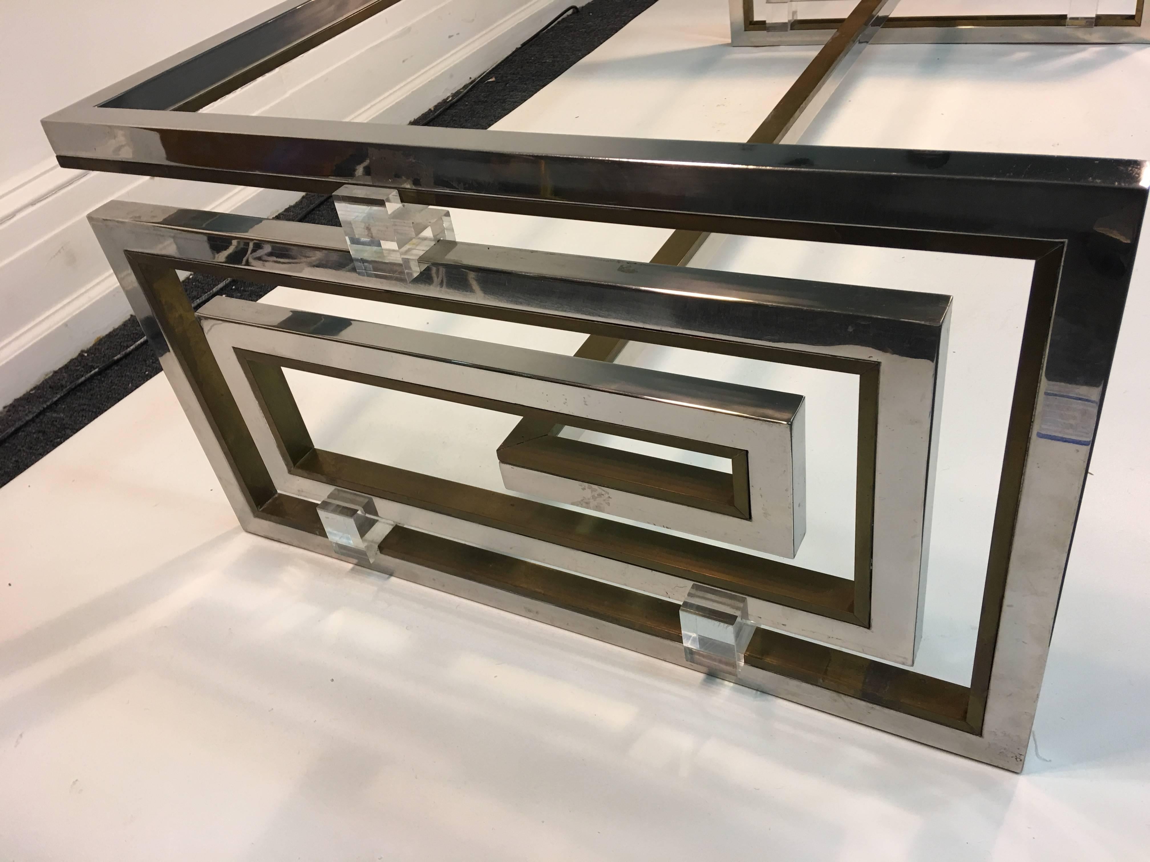 High Style 1970s Italian Design Coffee Table by Romeo Rega designed in a Modernist Greek Key Double Sided Form. Signed Romeo Rega Made In Italy .Composed of Chrome, Brass and Lucite. The rectangular glass fits in the square Lucite holders. The other