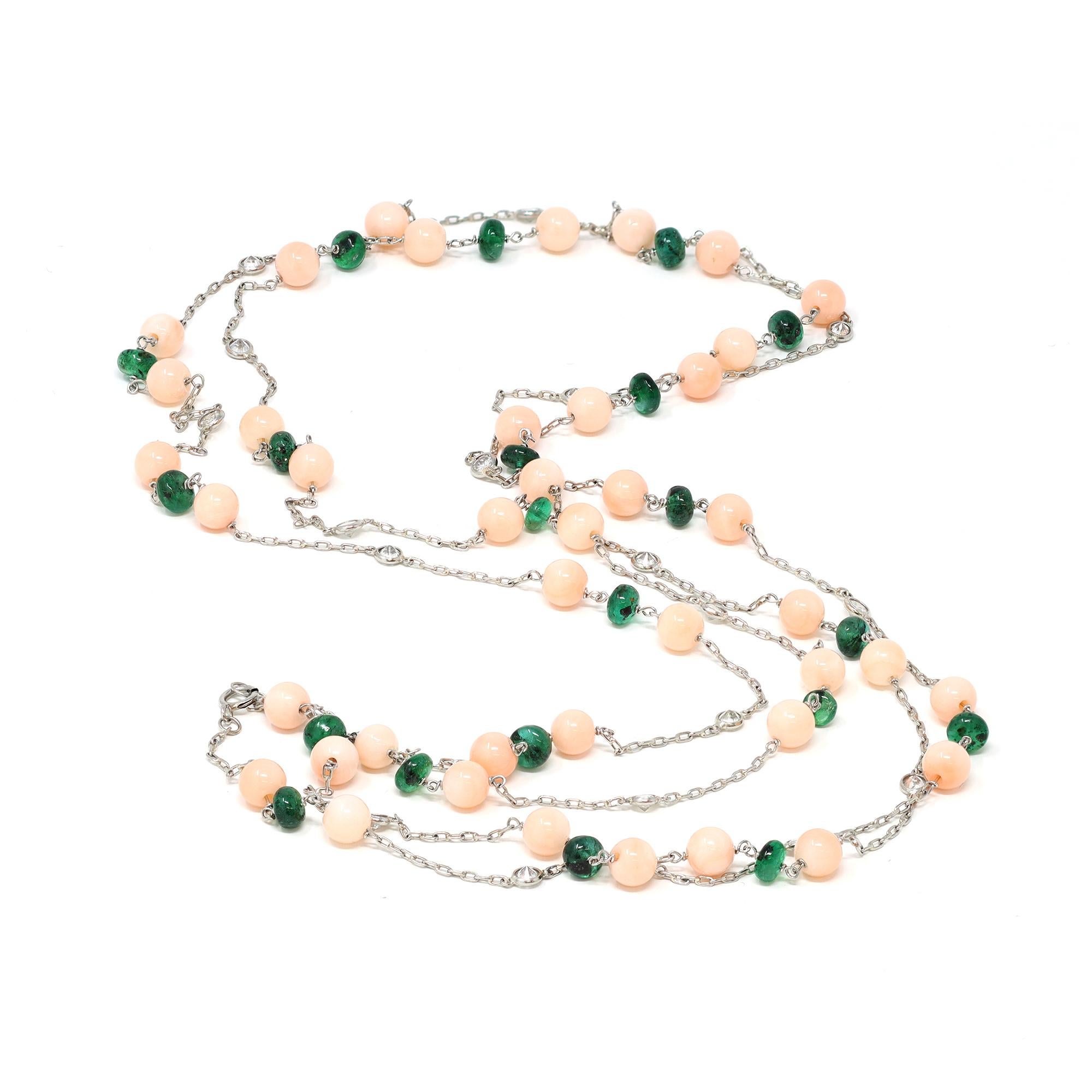 A dainty station platinum chain necklace. The hand made chain measures 52 inches long allowing to triple around the neck. It features a sequence of vintage Angel skin coral and polished emerald beads, accented by bezeled round diamonds. The diamonds