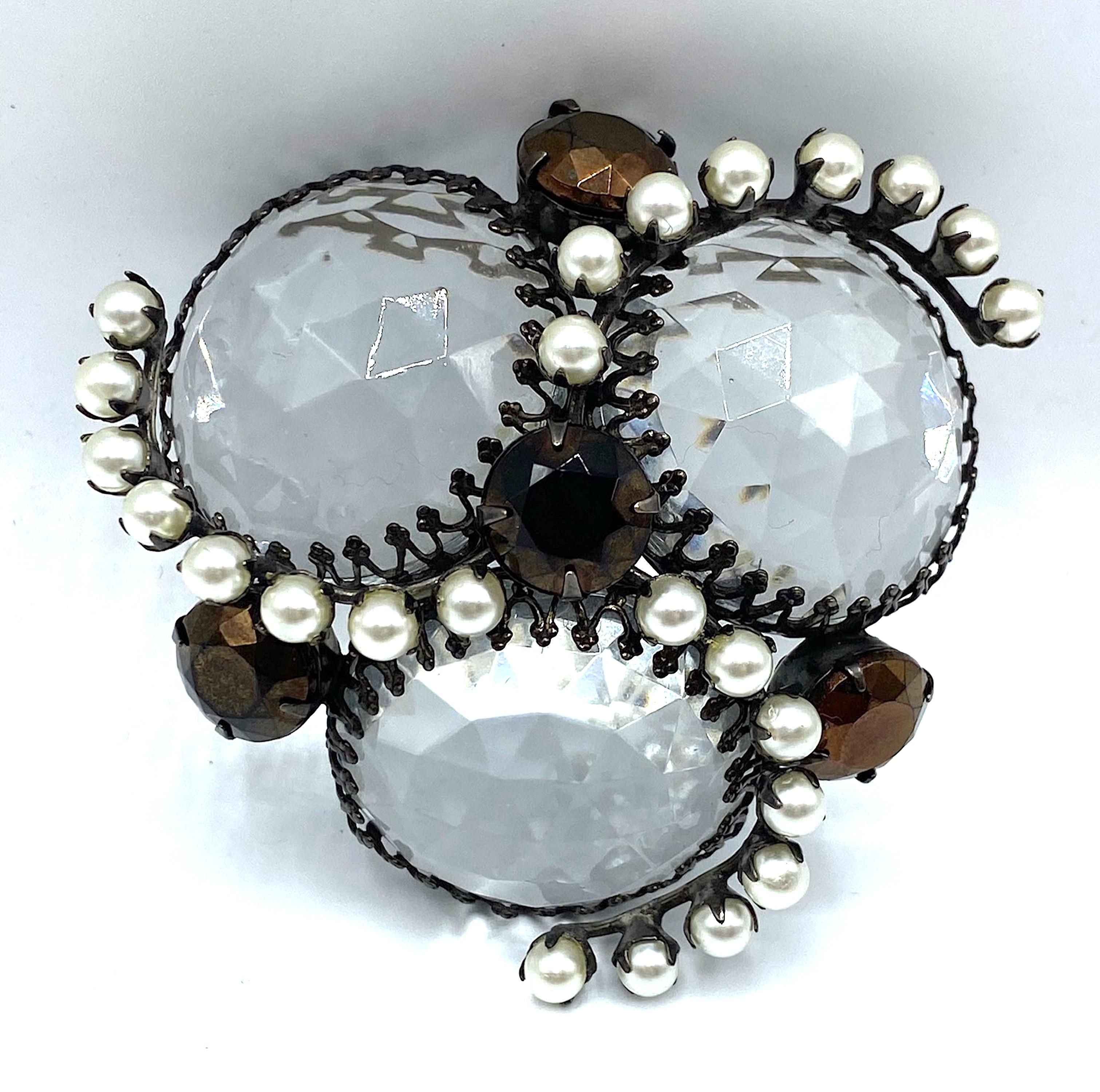 A rare and unusual design signed Schreiner, New York brooch from the 1950s. Charcoal grey gun metal patina on the metal. The design features three large faceted and clear crystal 1.13 inch diameter cabochons set into a domed mounting. The cabochons