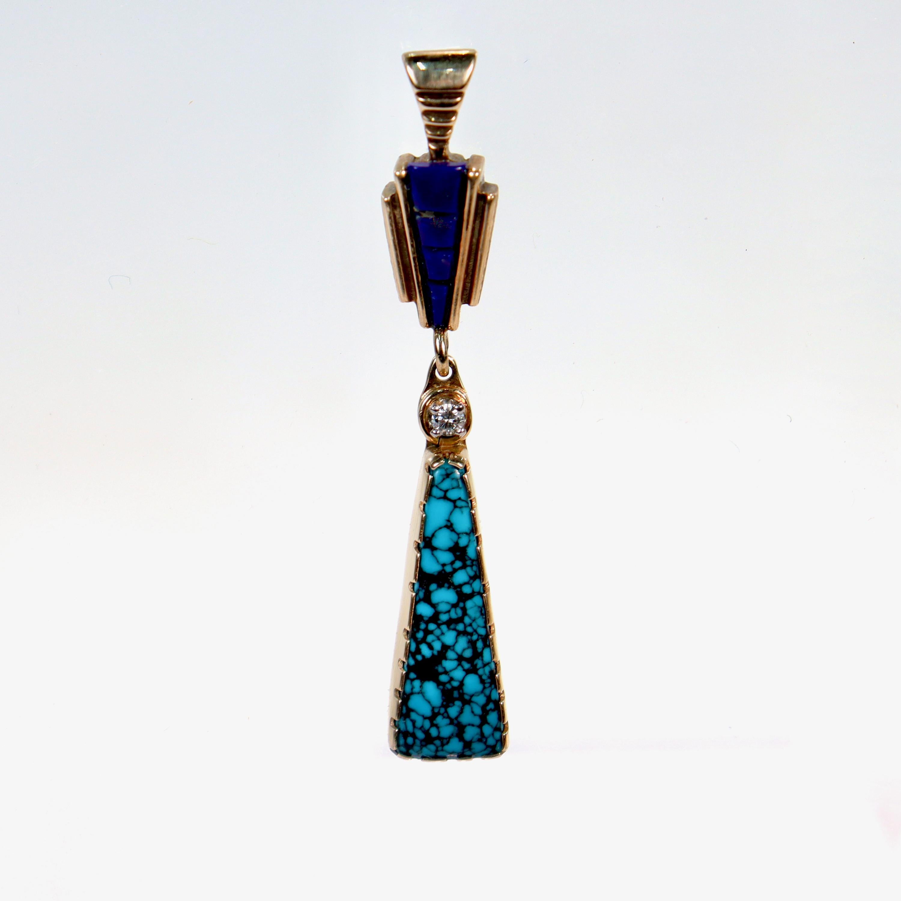 A fine Southwestern Native American style pendant.

In 14 karat yellow gold & set with a carved lapis gemstone, a triangular matrix turquoise gemstone, and a small white brilliant round cut white diamond. The lapis has a few small gold inclusions.