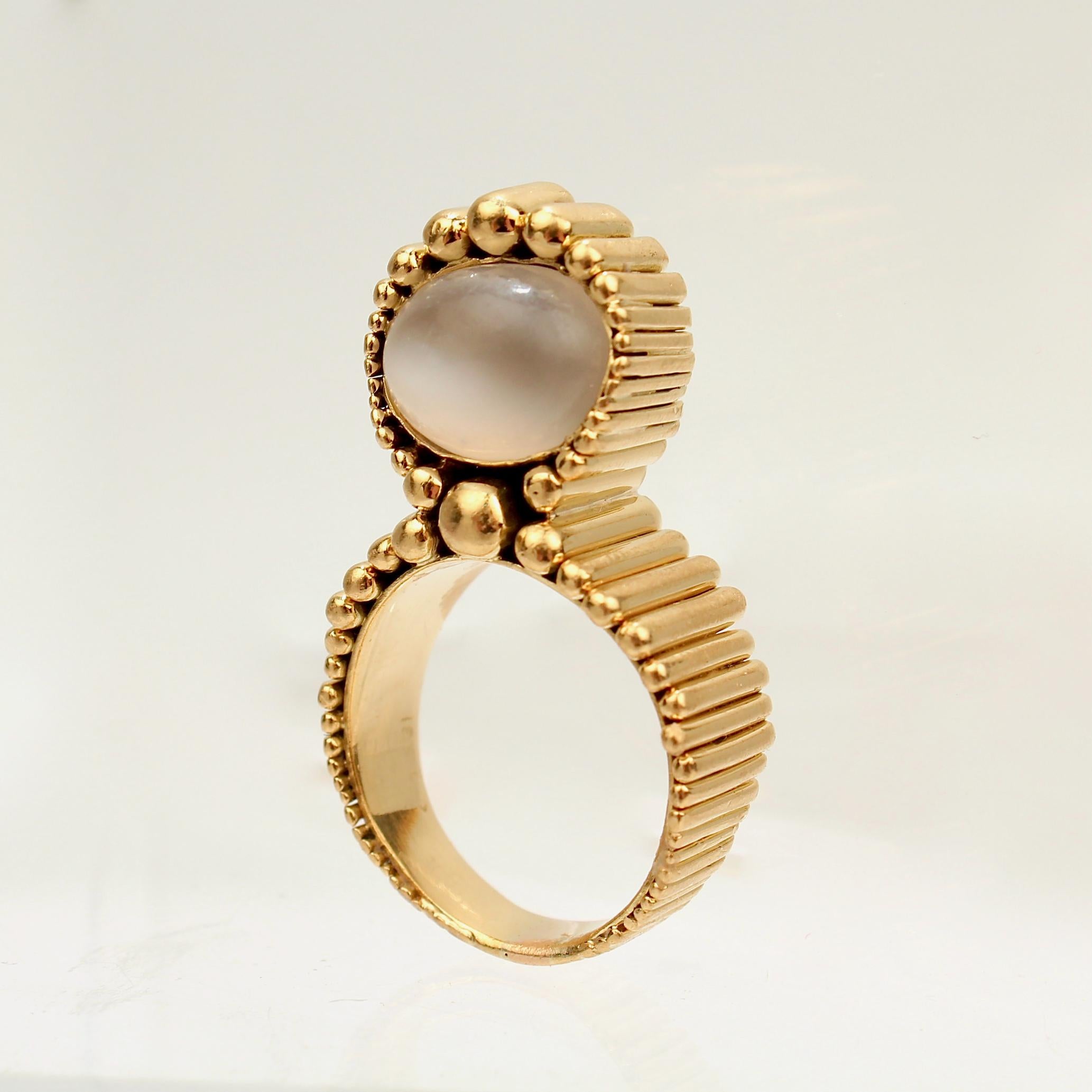 An incredible Space Age gold and moonstone ring.

Shaped as a 'figure 8' in 18k gold and set with a smooth oval, pebble shaped moonstone bead.

Designed by and marked for F. J. Cooper of Philadelphia. 

Simply amazing design at the intersection of
