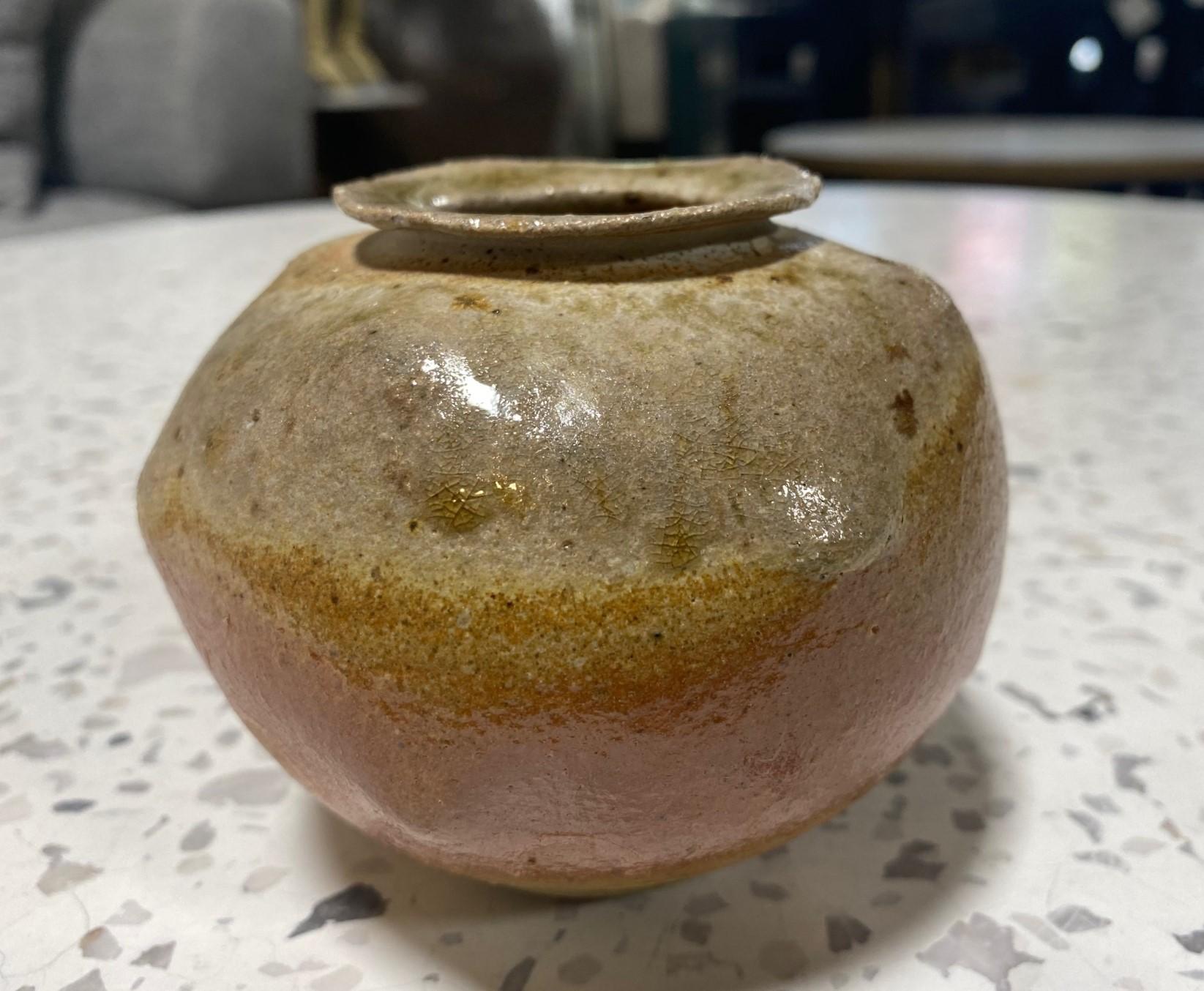 A gorgeously and sumptuously glazed studio pottery vase with irregular bumps and protrusions on the surface area, multi-colored earth-toned glazes, and a flared rim.  Quite an unusual design with a Wabi-Sabi look and feel to it (the Japanese