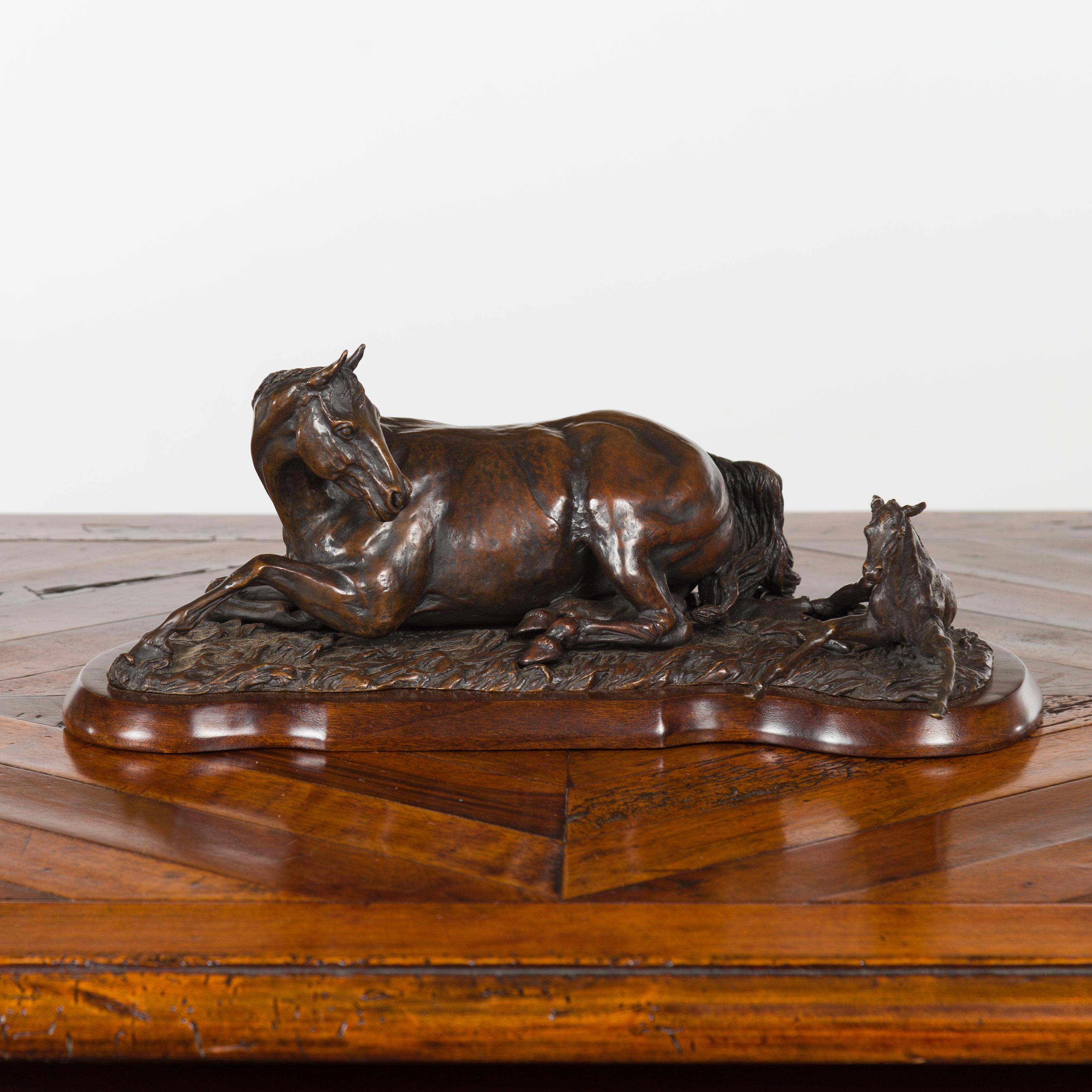 A cast bronze sculpture signed and dated Suzanne Fiedler 1974, depicting a horse and foal on wooden base. Cast by American artist Suzanne Fiedler in 1974, this bronze sculpture touches us with its heartwarming depiction of a mare and her foal laying