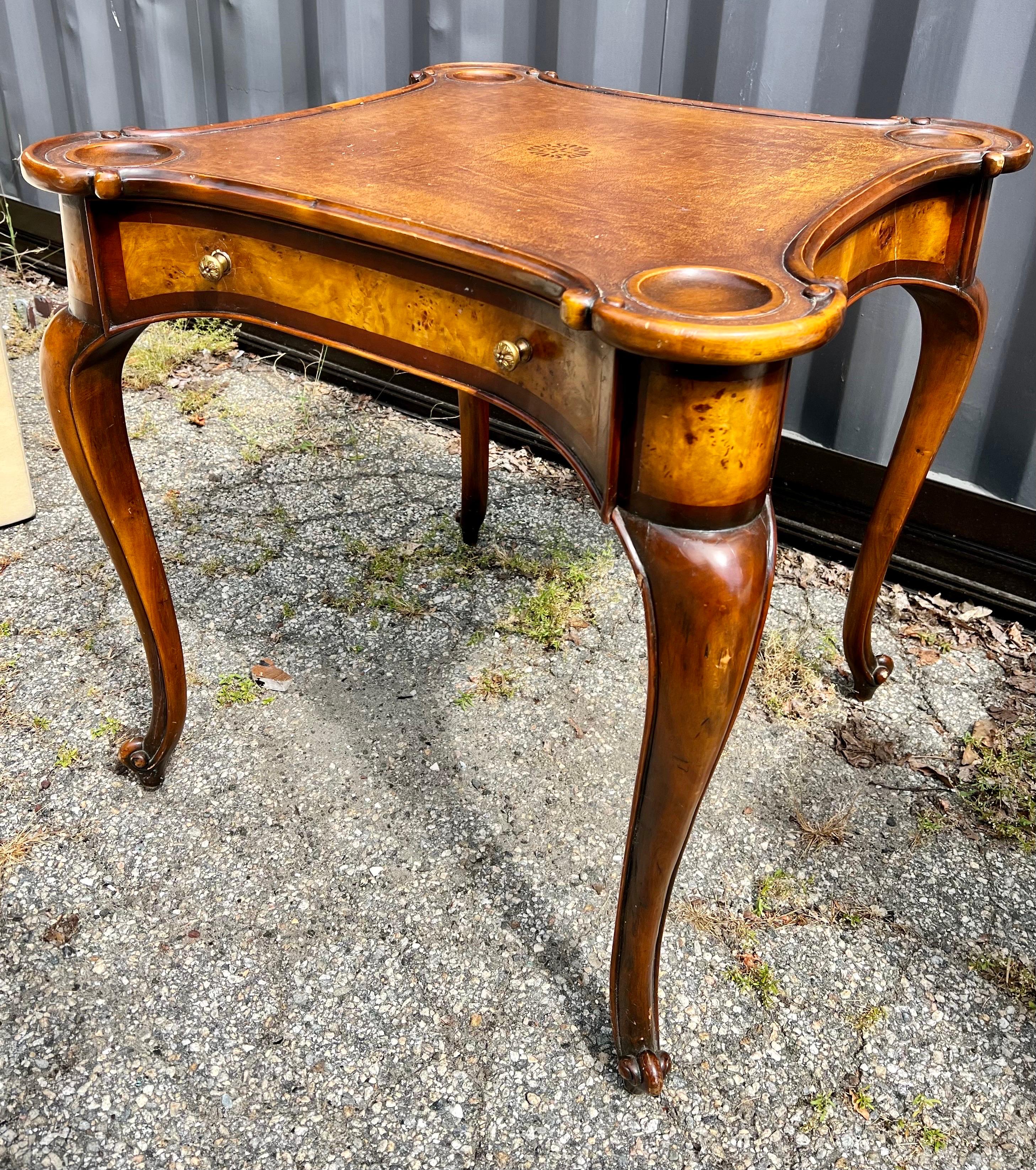 A elegant scalloped edge Theodore Alexander game table that features one center drawer. The piece has some age appropriate wear as one can see from the pictures but it is still a wonderful addition to almost any aesthetic. Great scale and better