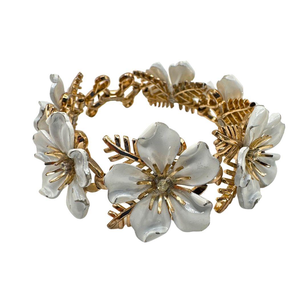 Neaklace Length: 7″

Bin Code: M2 / P15

Embrace the timeless elegance of our Signed Trifari Dogwood Vintage Enamel White and Gold Flower Bracelet. This exquisite fashion bracelet showcases the renowned craftsmanship and sophistication of Trifari, a
