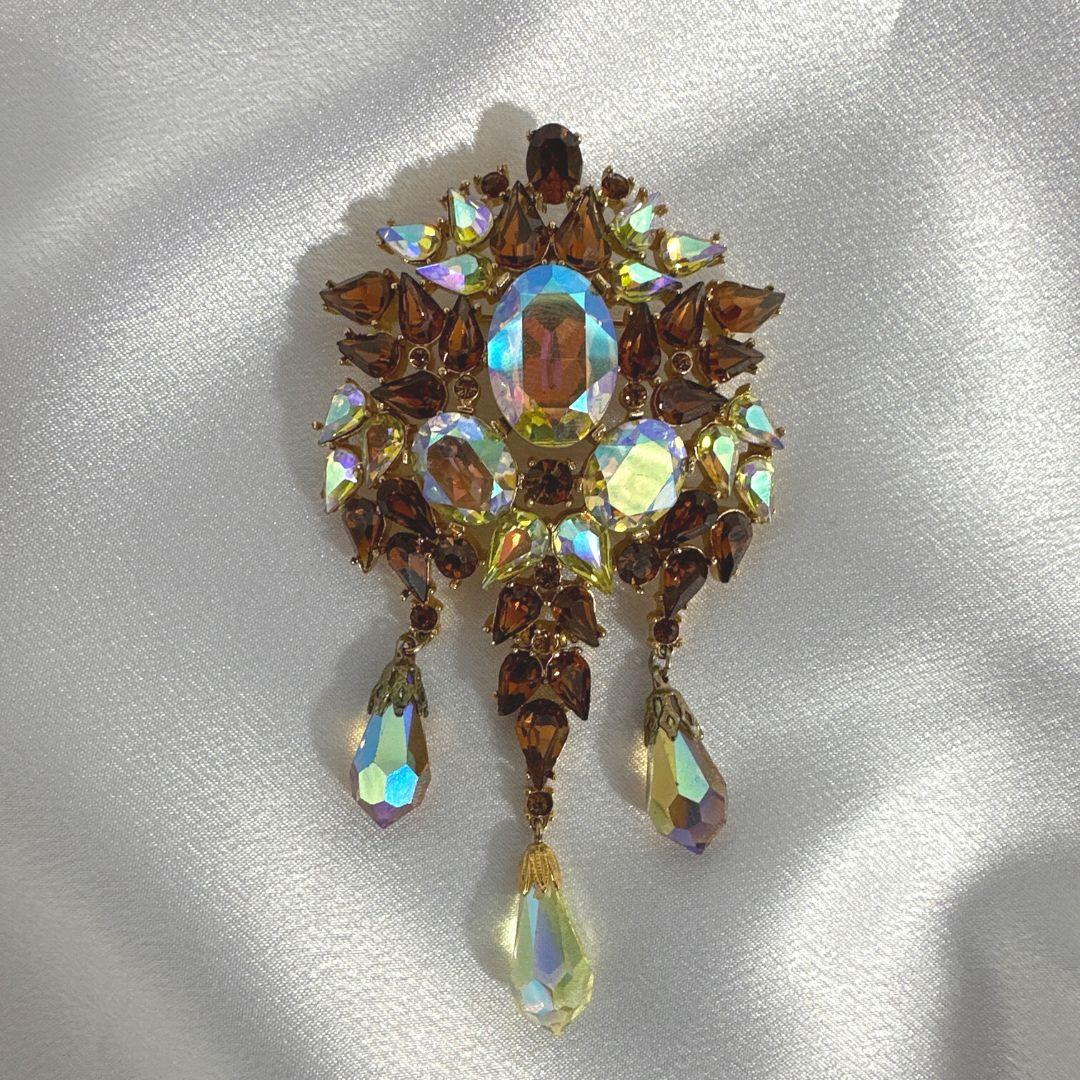 Indulge in timeless elegance with this Signed Trifari Vintage Gold Multi-Color Glass Drop Brooch, a captivating piece that effortlessly combines vintage charm and sophistication. Crafted with precision, this brooch is adorned with a stunning array