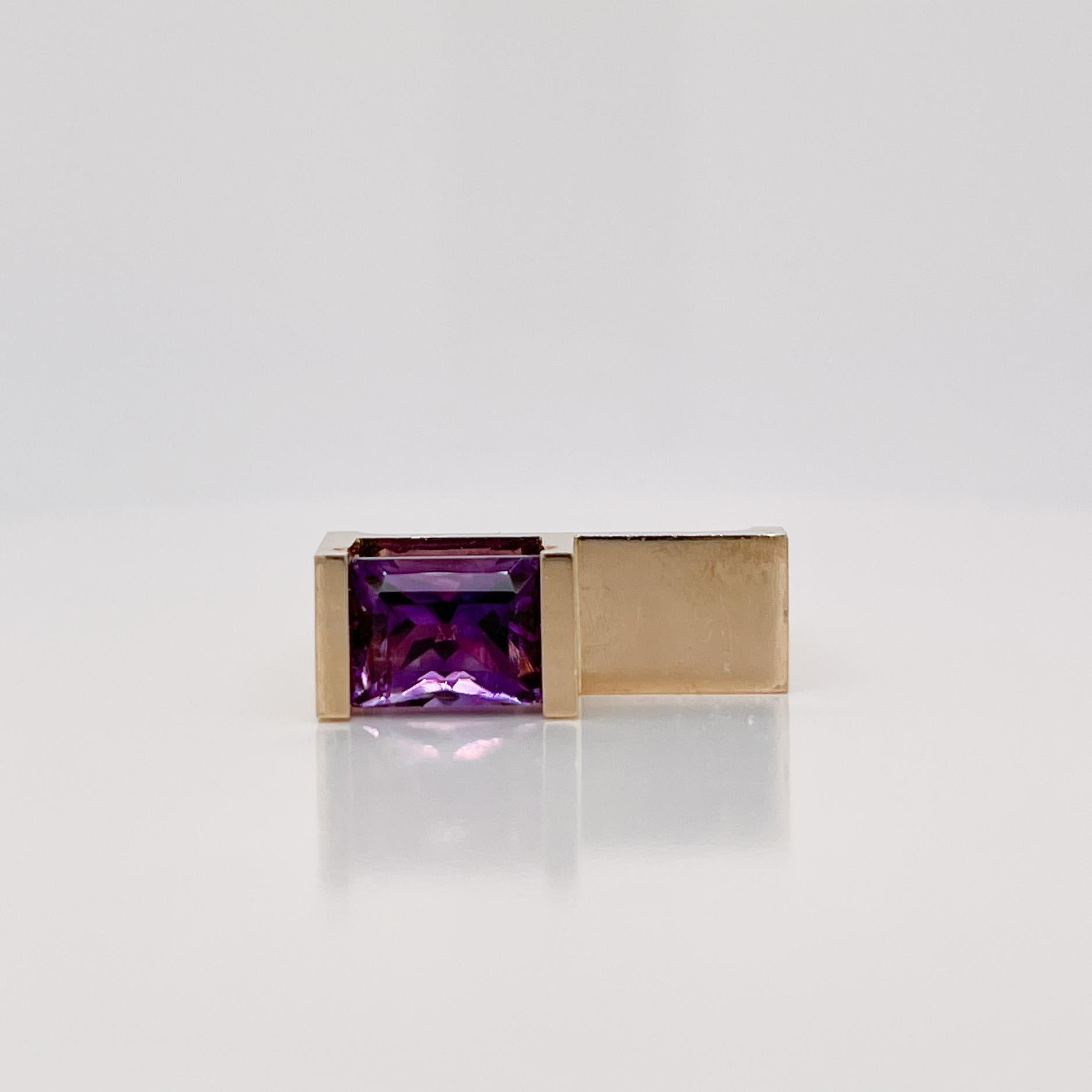 A very fine signed gold and amethyst cocktail ring.

By Trisko. 

In 14k yellow gold and prong set with and emerald cut amethyst gemstone on a square band.

Simply a great architecturally inspired ring by Trisko!

(The final images depict this ring