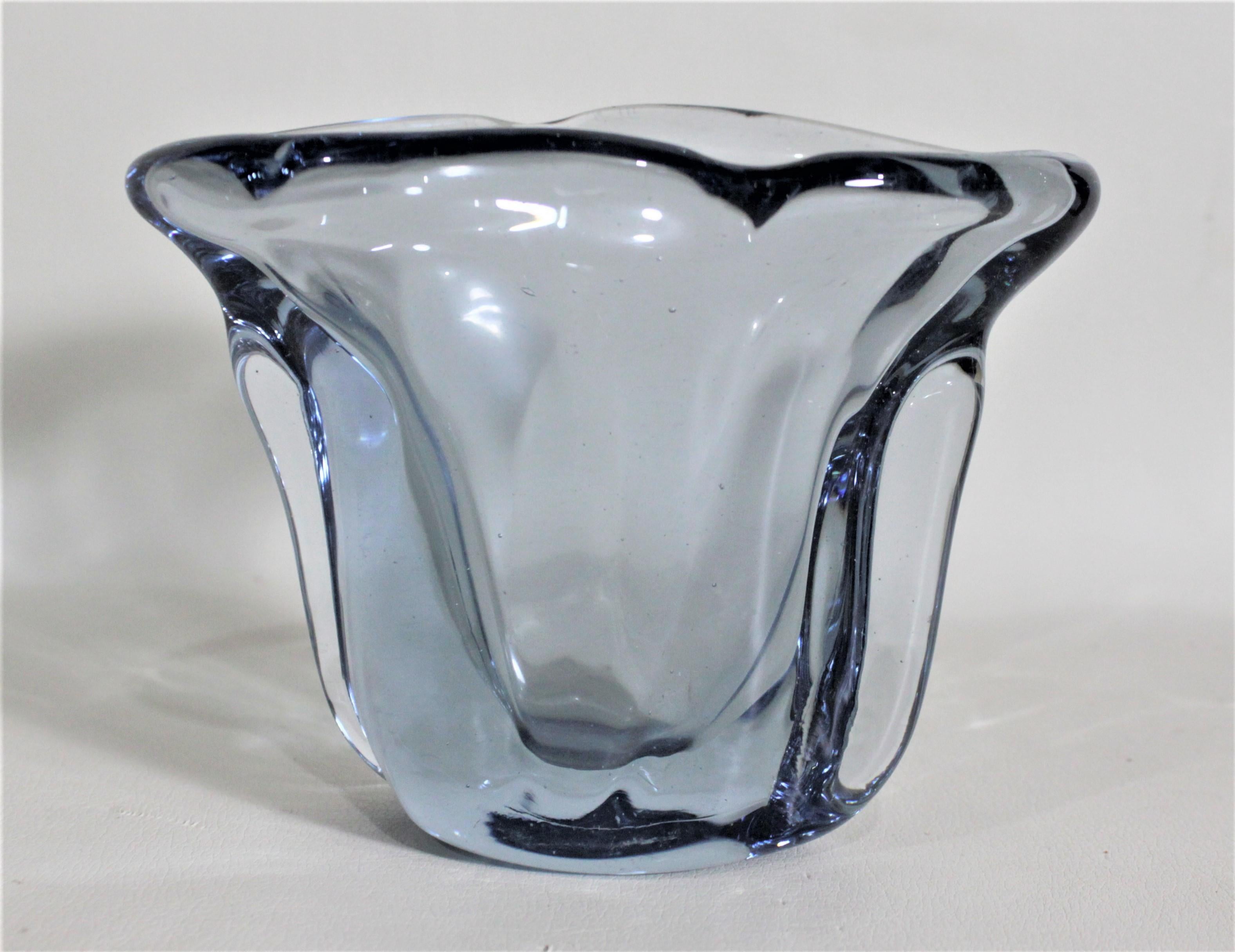 This clear ice blue art glass vase was made by the renowned Venini Murano art glass factory in circa 1970, in the Mid-Century Modern style. This vase is made of thick blue glass with a pulled fluted top with an off-center rim division that draws the