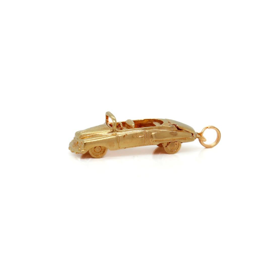 A fine vintage American gold charm.

In 14k yellow gold.

By the American Charm Company.

In the form of a Mid-Century convertible car or automobile with a fixed bail to the front, a hinged, functional trunk, and wheels that spin.

Simply a