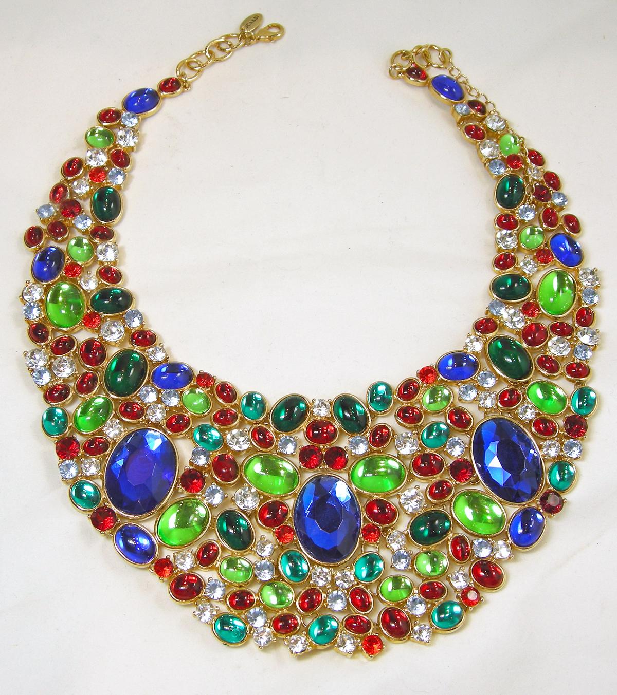 This magnificent, large bib necklace is designed by Arnold Scaasi.  The necklace is embodied with multi colors of green, blue, red, aquamarine and clear crystals mixing faceted and cabochon stones.  It is signed “Scaasi” on the tag and on the back. 