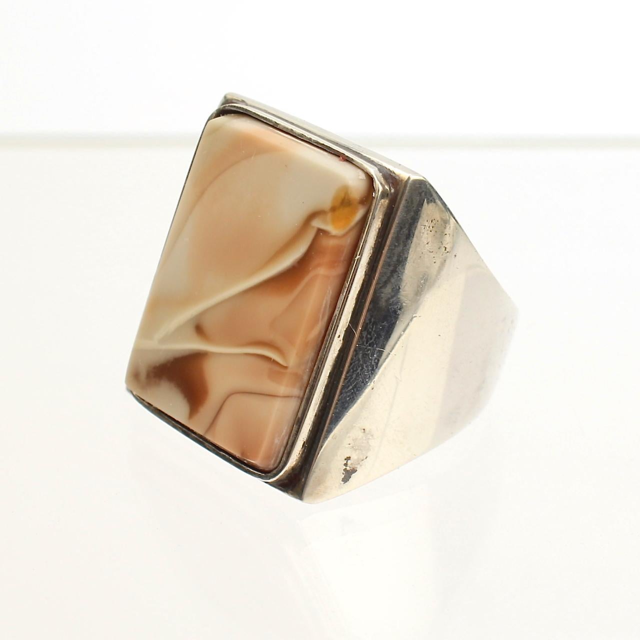 An impressive, heavy Wesley Emmons ring.

Comprised of sterling silver, this stoutly made modernist ring is set with a flat rectangular polished agate cabochon.

Emmons was an important jewelry maker in Philadelphia during the mid-20th century. He