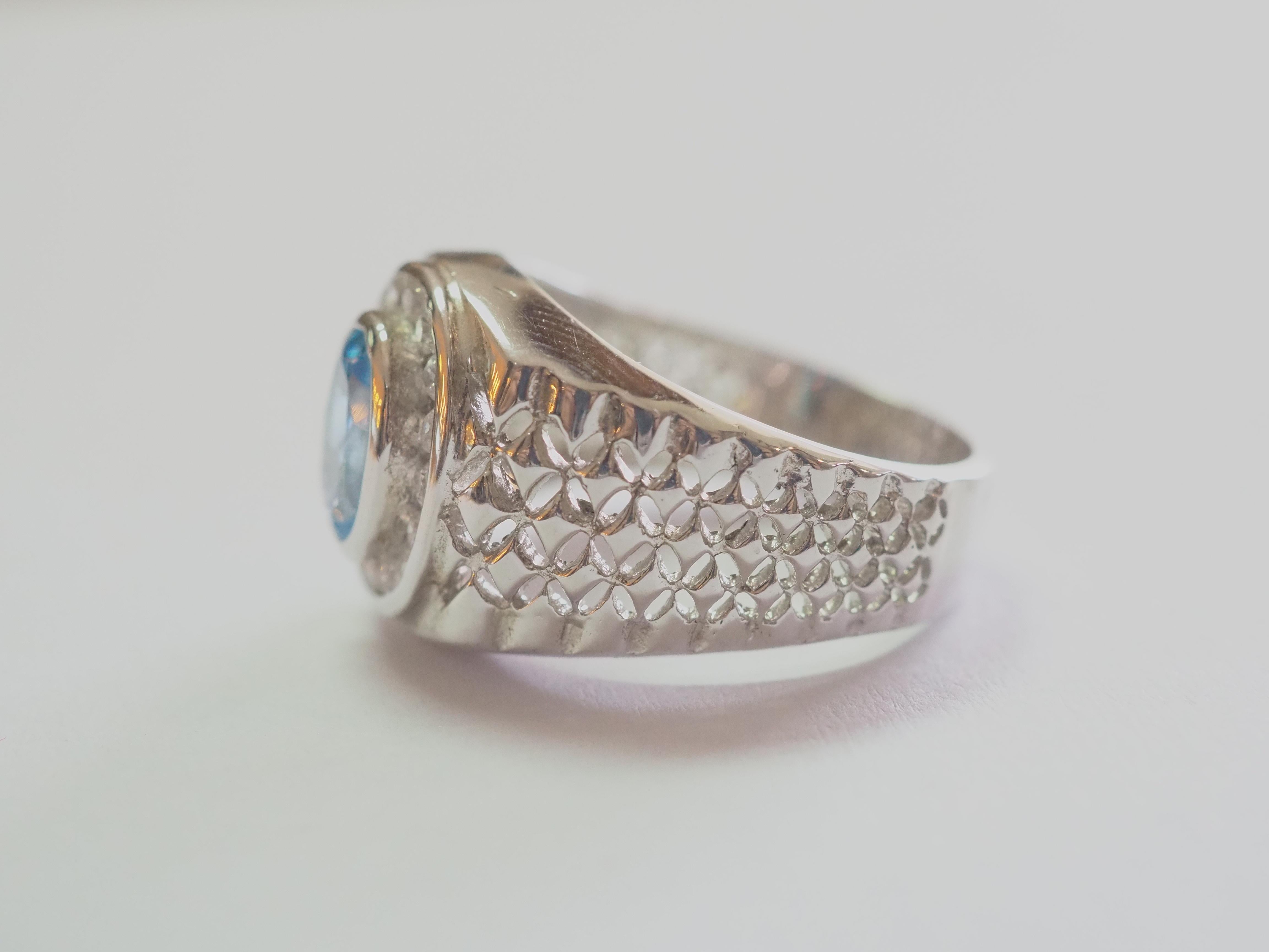 This ring is a stunning signet ring in solid sterling silver. The ring is decorated by natural oval blue topaz bezel set in the middle. The surrounding white stones are cubic zirconia. The unique engraving pattern on the band is good to look at. The