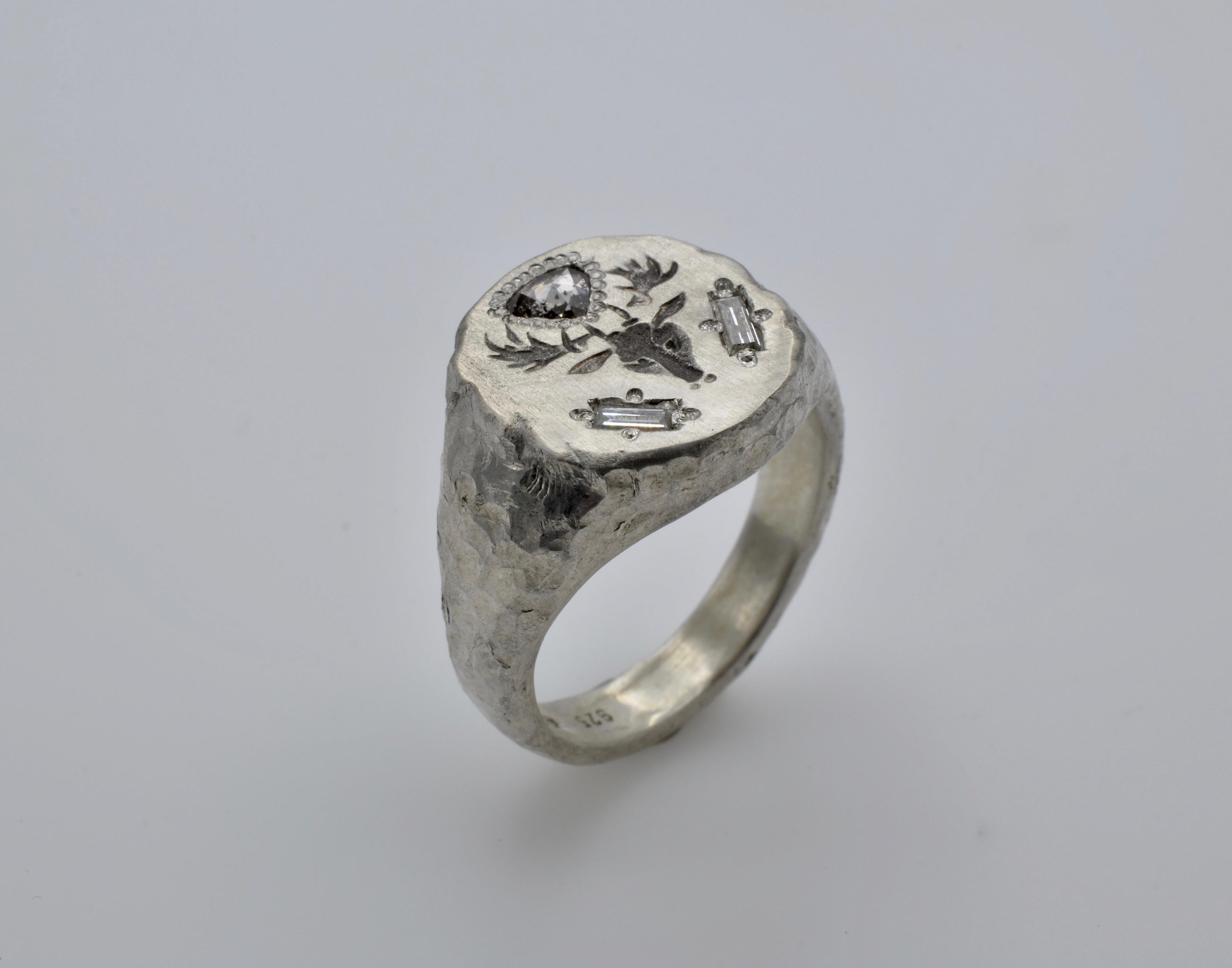 Traditional shape of a signet ring, with the particularity of the hammered texture in silver and set with diamonds. The two baguettes diamonds are 0.10 carats TW on the sides of the Deer head that adds a modern look to the ring. The top is showing