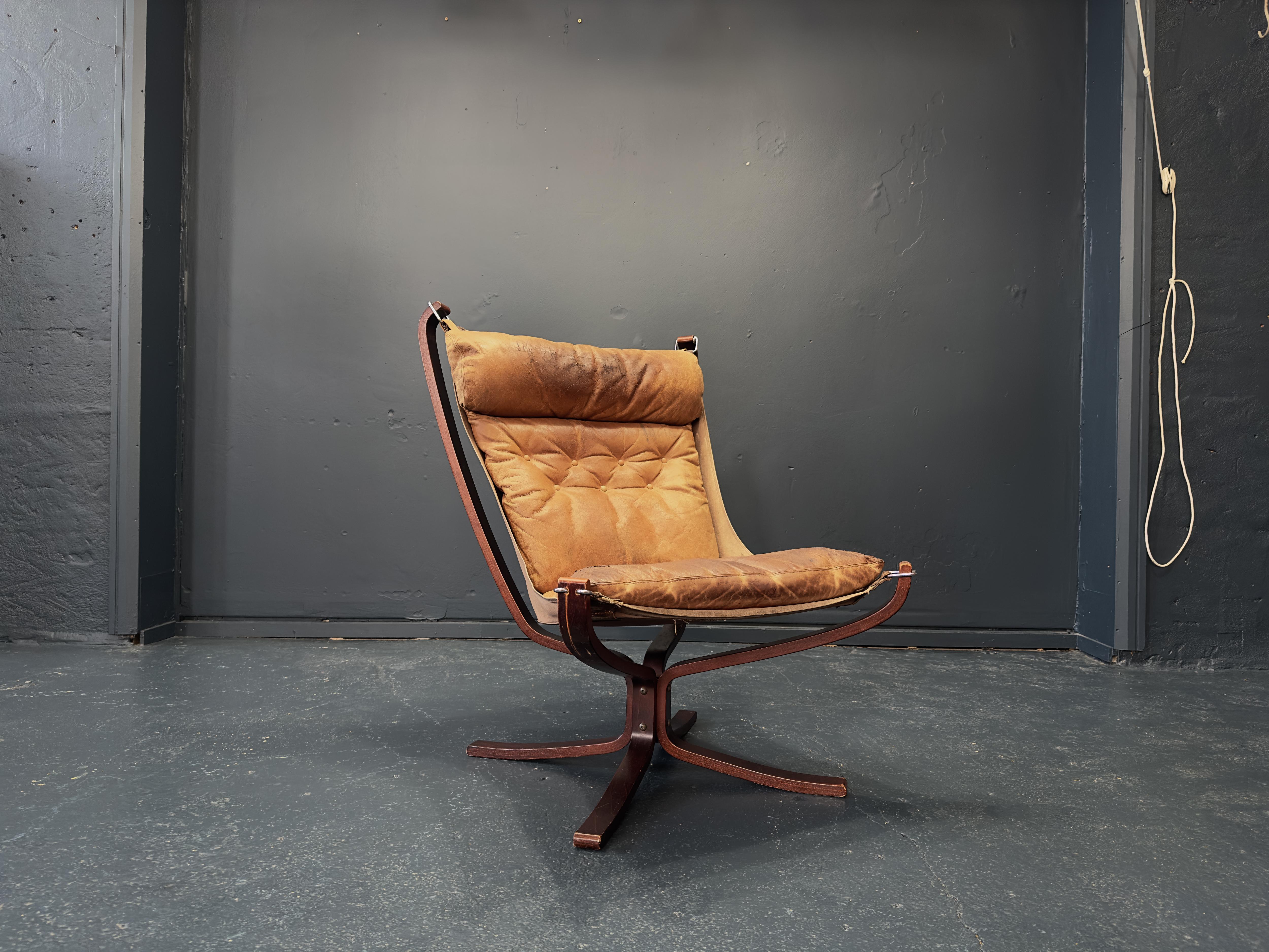 A later version of the original 1970s Falcon Chair designed by Norwegian interior architect Sigurd Ressell. Upholstered in light brown patinated leather and maintaining the original armless shape, the sturdy beech base is stained to emulate