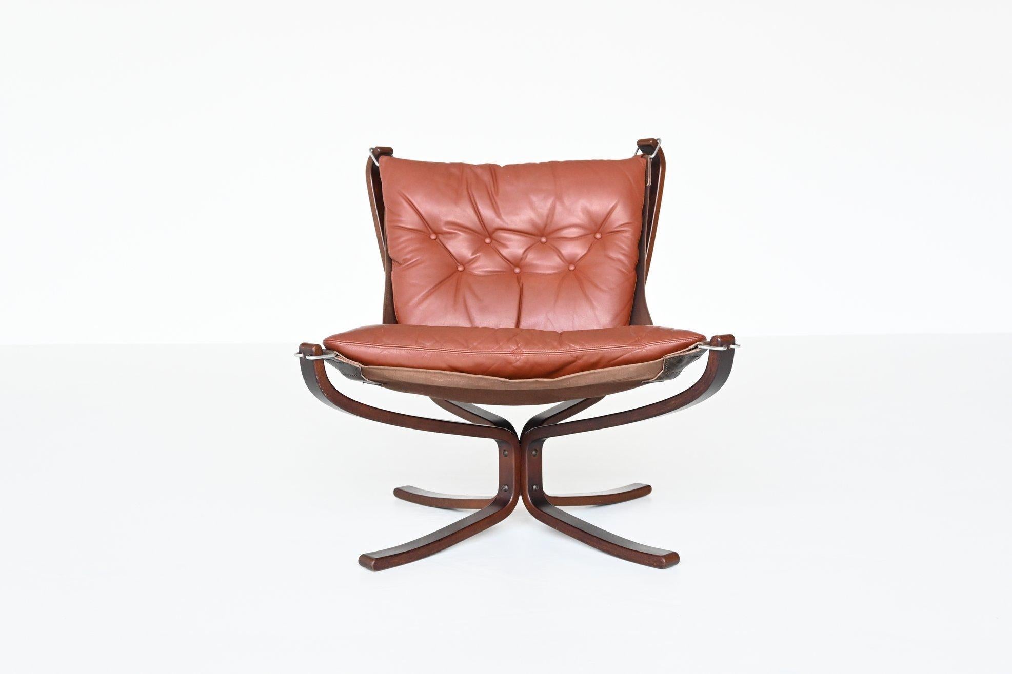 Iconic X-framed low back Falcon lounge chair designed by Sigurd Ressell for Vatne Mobler, Norway 1970. It features a curved stained beech wooden frame, canvas sling and cognac brown leather cushion. The hammock style floating seat has become a