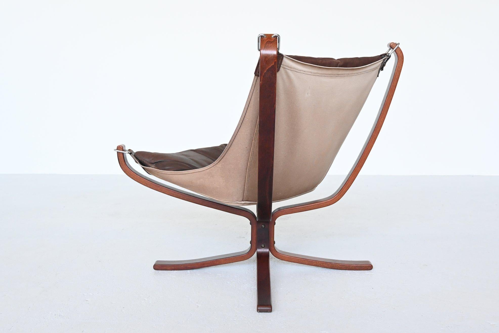 Iconic X-framed falcon lounge chair designed by Sigurd Ressell for Vatne Møbler, Norway 1970. It features a curved beech wooden frame, canvas sling and dark brown leather cushion. The hammock style floating seat has become a design Classic and is