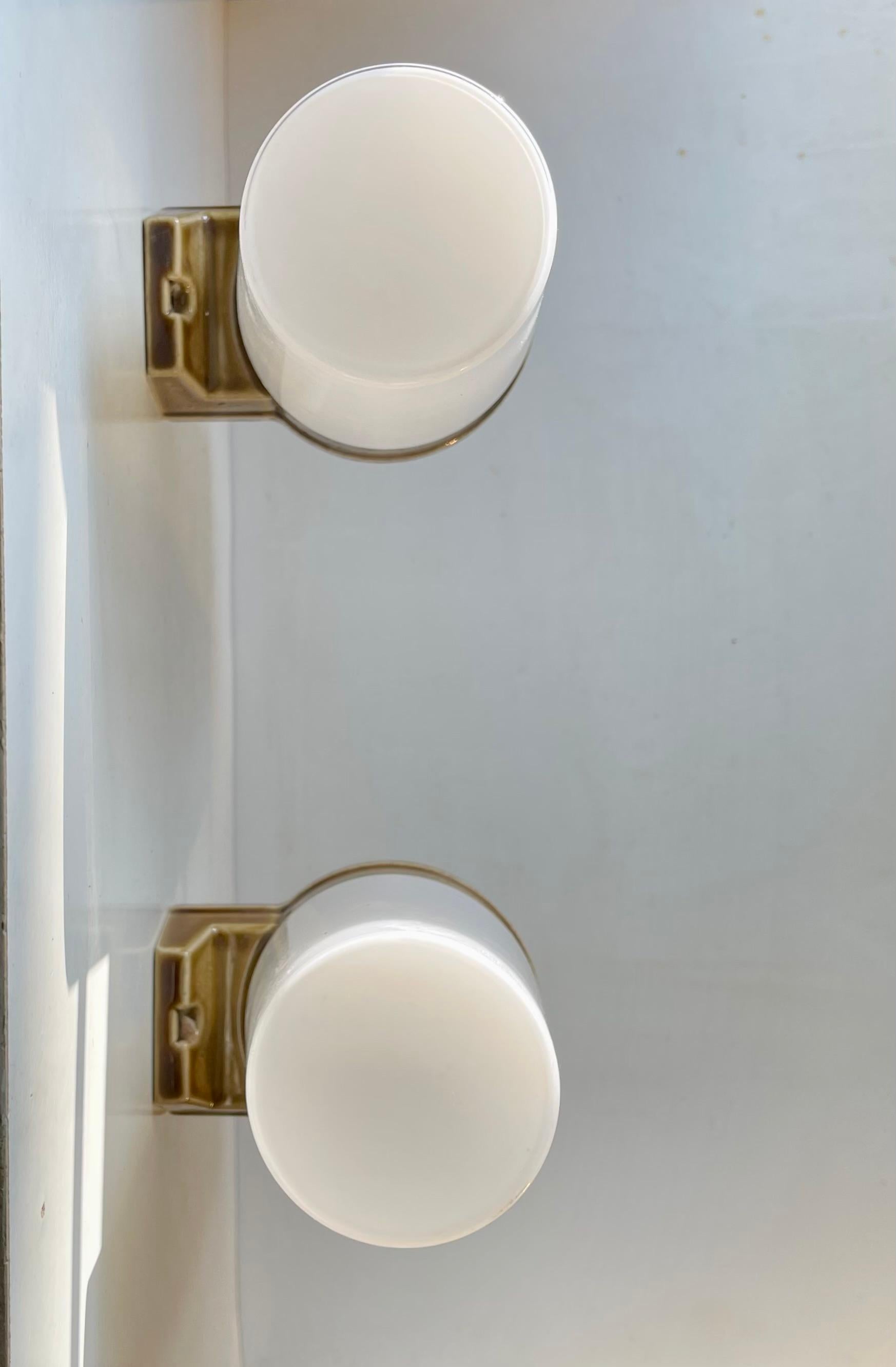 A pair of sconces suitable as bathroom or Toilette lighting. They were designed by Prince Sigvard Bernadotte for the swedish company Ifö during the 1960s. These were manufactured in the 1970s. This model 6065 features glazed mounts each mounted with