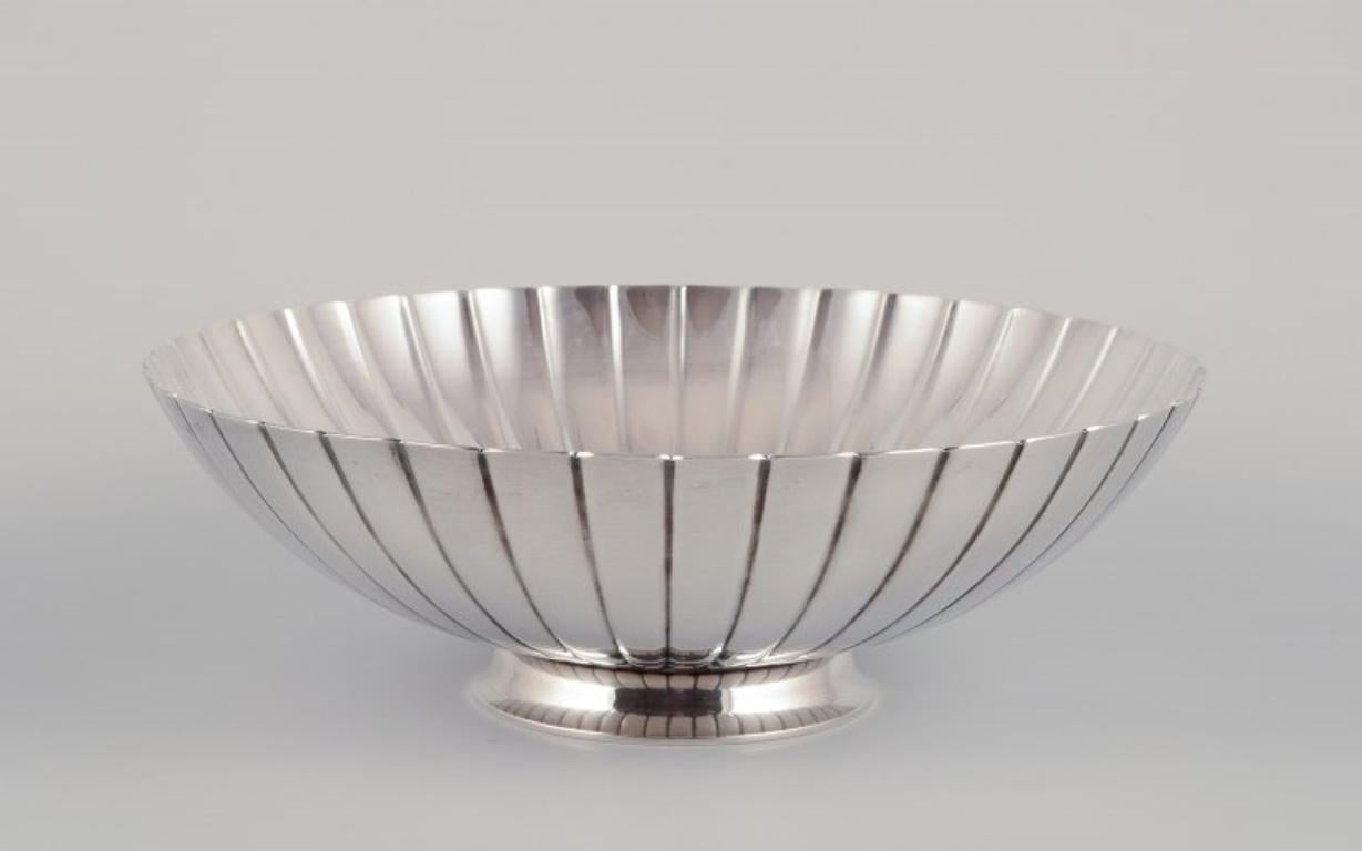 Sigvard Bernadotte per Georg Jensen. 
Ciotola grande in argento sterling con design a coste.
Model No: 856B
Timbro con marchio post-1944.
Progettato nel 1943.
Condizioni perfette.
Dimensioni: D 25,5 cm. x H 8,2 cm.