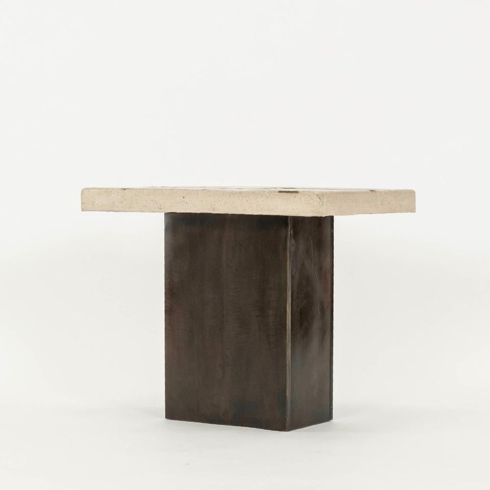 Signed by the artist, this side table features molten bronze poured onto a hand cast formed stone allowed to settle and solidify in the natural dips of the artist's unique form.. The sudden temperature clash caused by the heat of the molten bronze