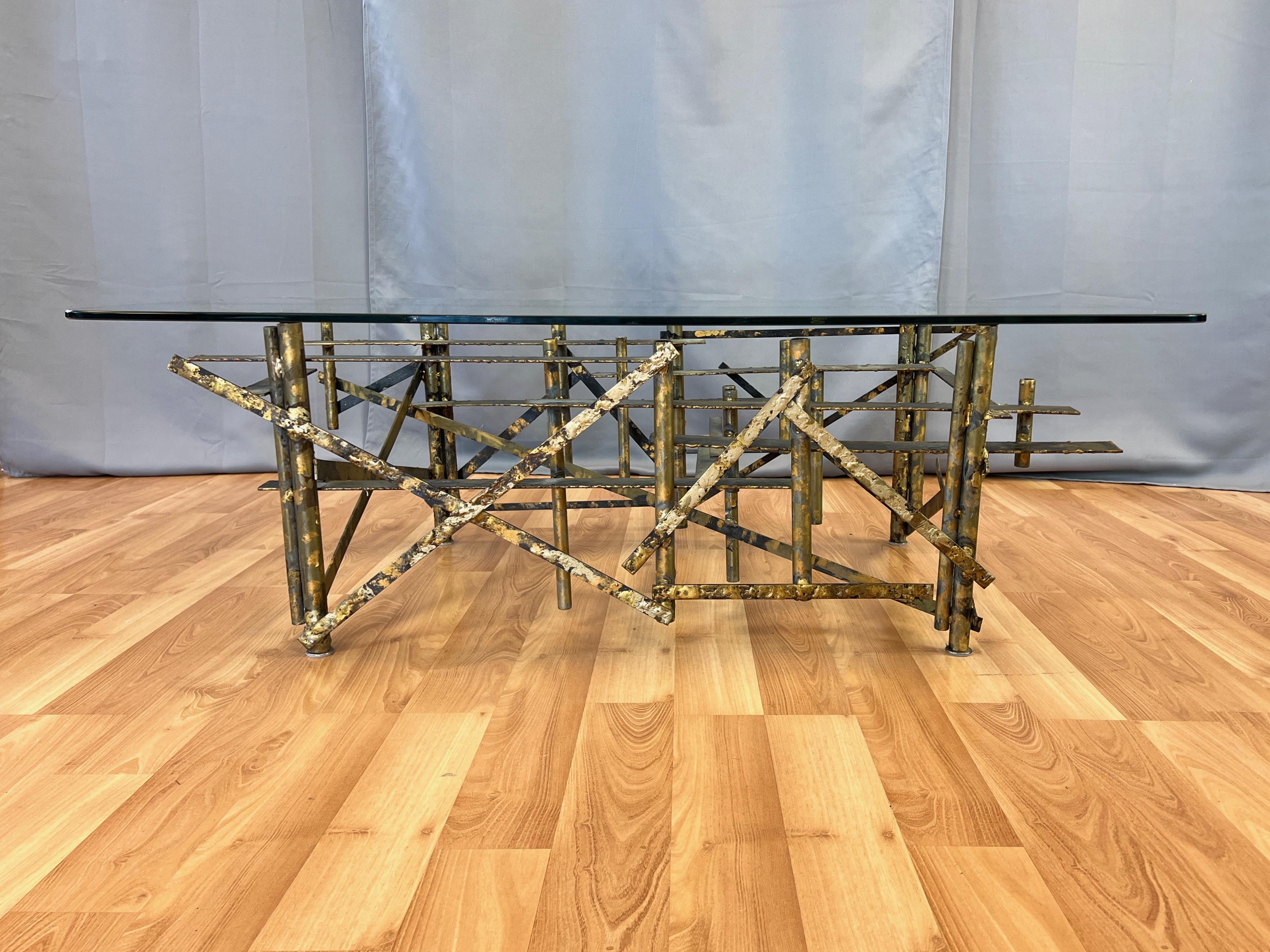 A very striking and uncommon Brutalist steel coffee table done in the manner of Silas Seandel, Marc Creates, or Curtis Jeré, with hand-painted and gilt finish and original glass top.

Abstract sculptural form comprised of welded steel pipes of two