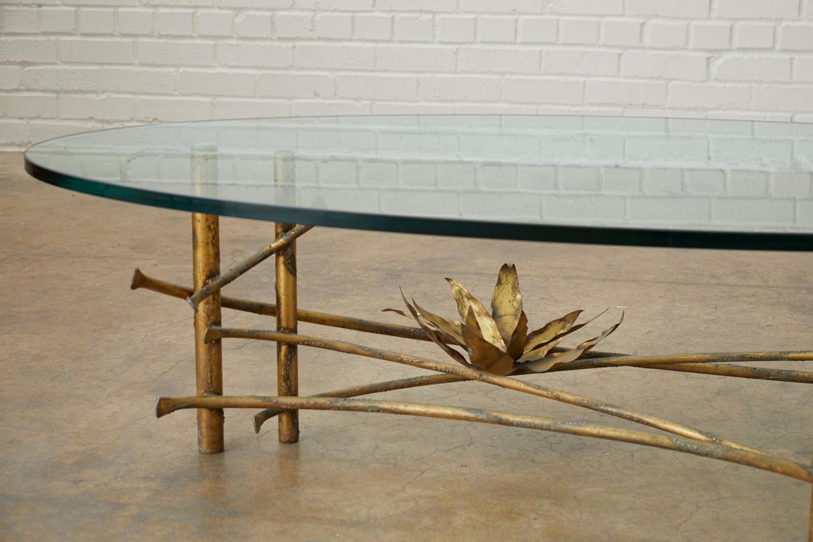 Stylish Mid-Century Modern coffee table or cocktail table made in the manner and style of Silas Seandel. Features a large iron base with a gilt bronze finish. Graceful branches connect pairs of legs with a delicate waterlily or lotus blossom mounted