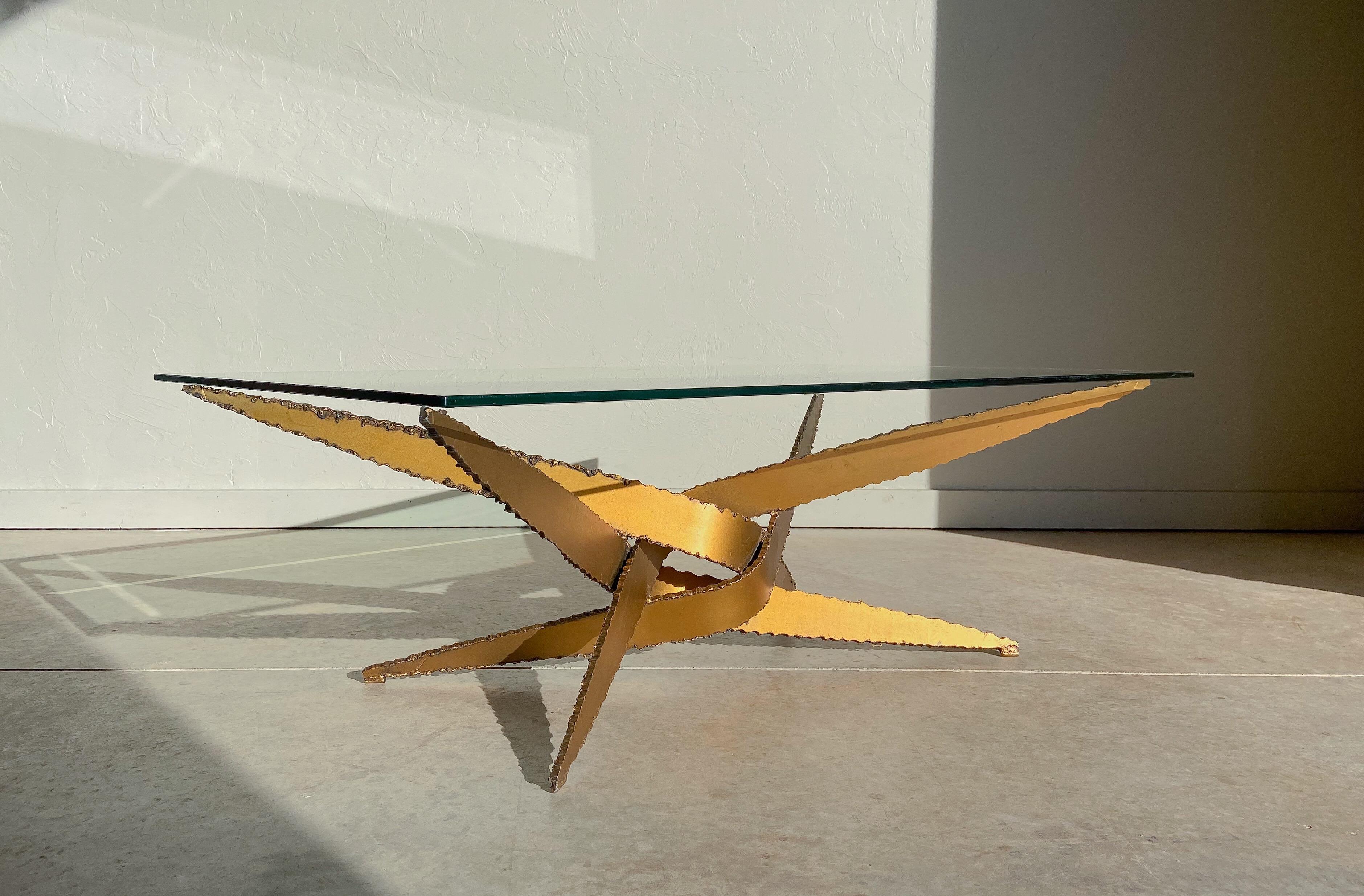 A vintage coffee table in the style of Silas Seandel.

Made from four separate torch cut steel elements that have been formed and welded into shape. It's heavy steel construction and raw edges give the table a masculine presence; but this is