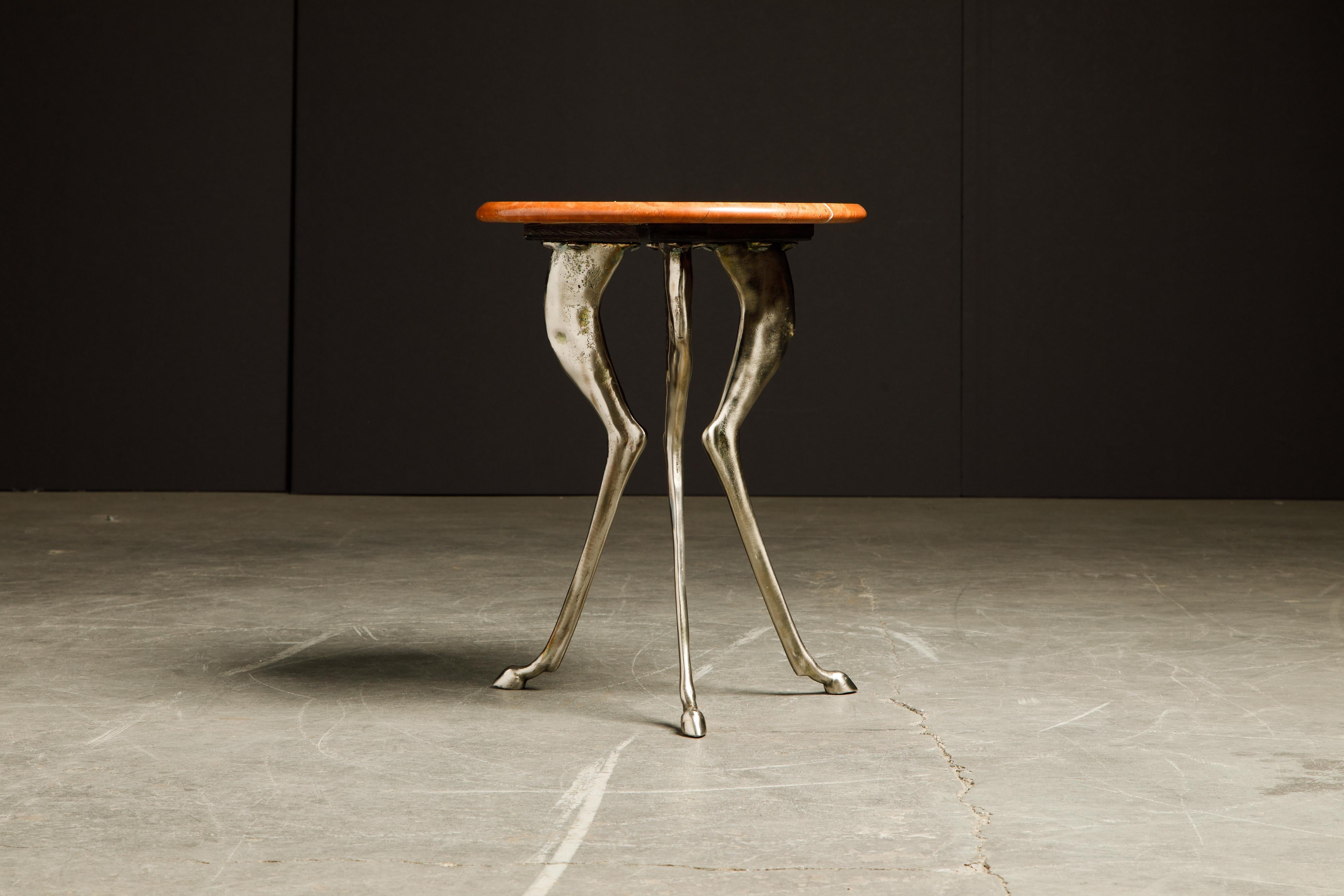 An incredible aluminum three-legged anthropomorphic side table, in the style of Silas Seandel and John Dickinson, with some similarities in concept to the 'African' plaster tables. This amazing piece is very heavy and topped with a beautiful red