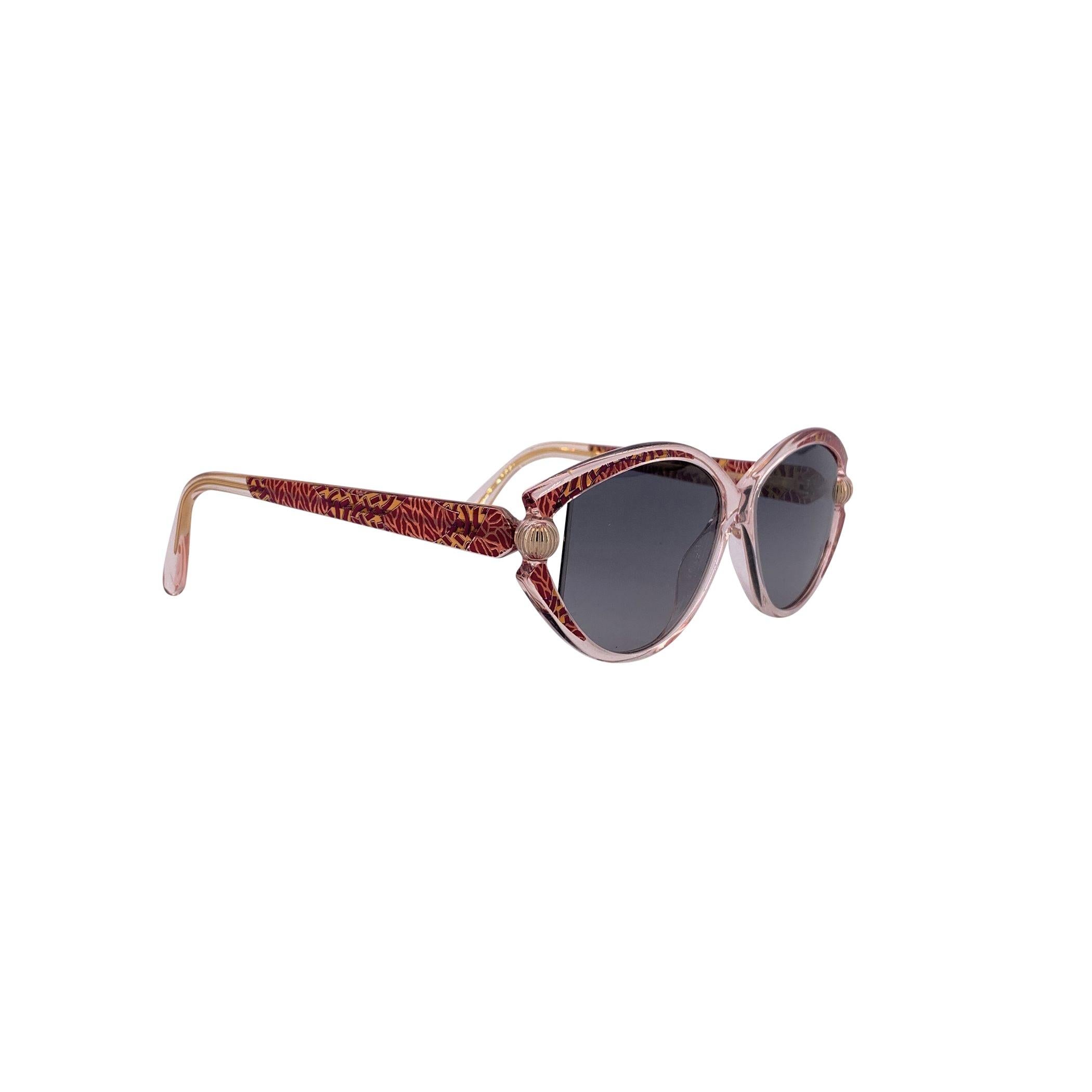 Step into the refined elegance of 1980s Austrian design with these Silhouette Vintage Oval Sunglasses M 1816/20 C2691. Their transparent front frame is adorned with a red motif streaked with light pink, flowing seamlessly onto the temples for a