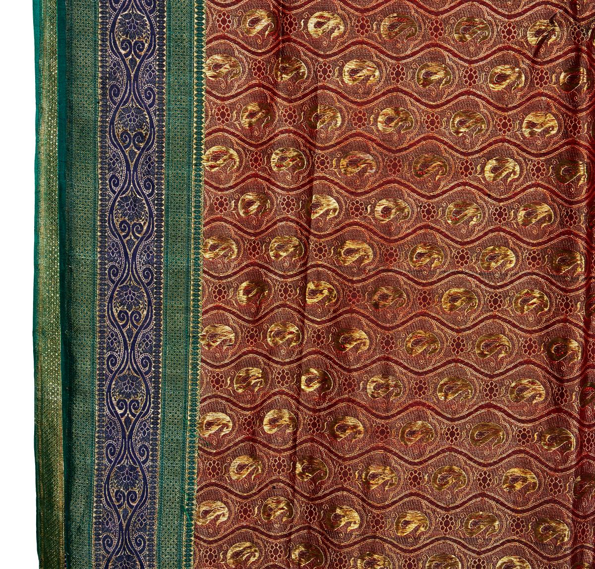 A lavish sari from India, hand-crafted out of a single piece of silk brocade. Mid 20th Century, circa 1970. Gold Paisley brocade on burgundy / deep red silk, with blue, green and gold lateral trim. Fully reversible with opposite colors. 

Can be