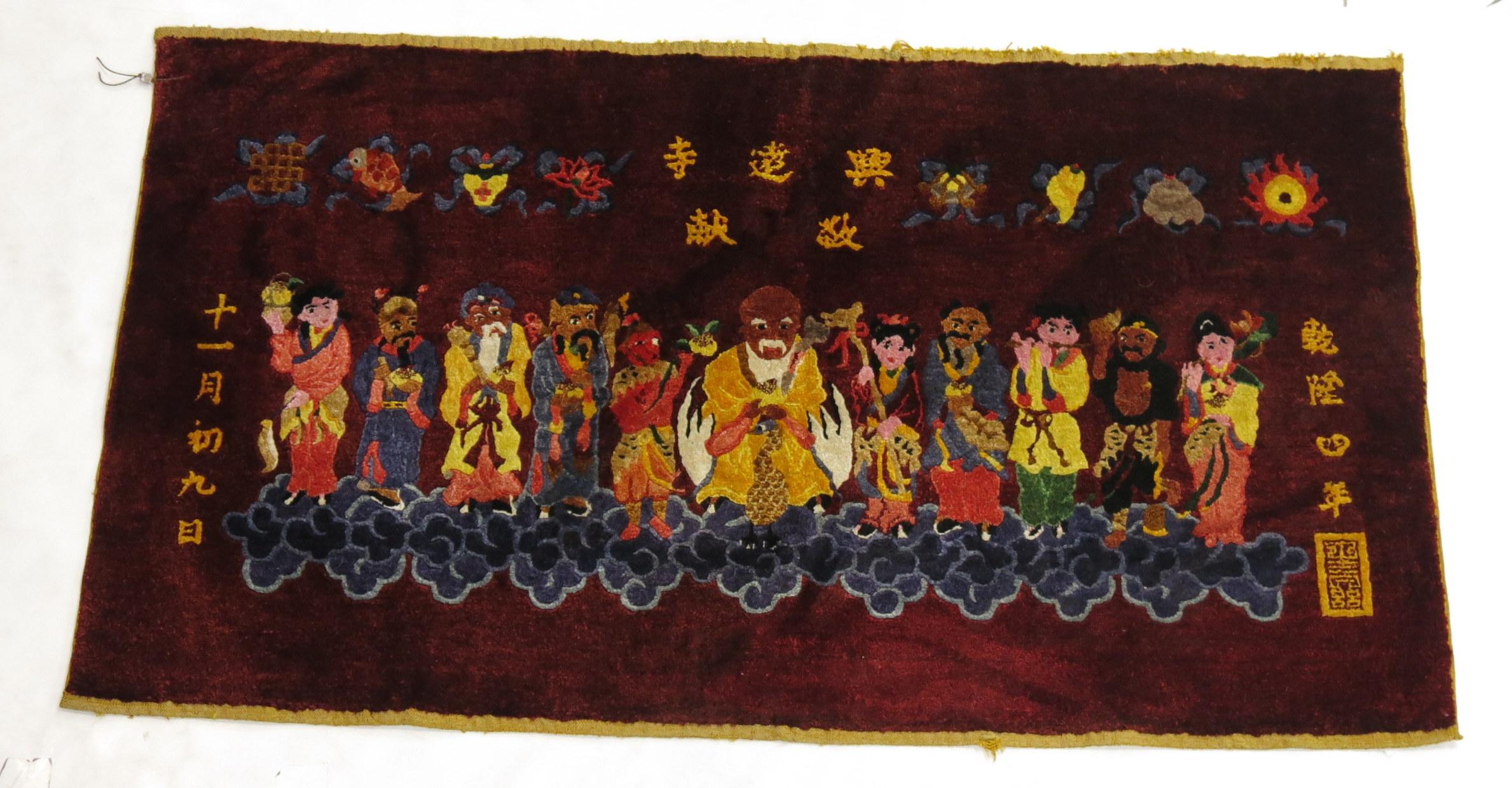 A Chinese silk pictorial rug. On a border-less burgundy red ground, 11 Immortals stand on clouds .Each immortal has its own unique colorful outfit or costume. The calligraphy most likely shows that it was woven somewhere in Beijing although we are