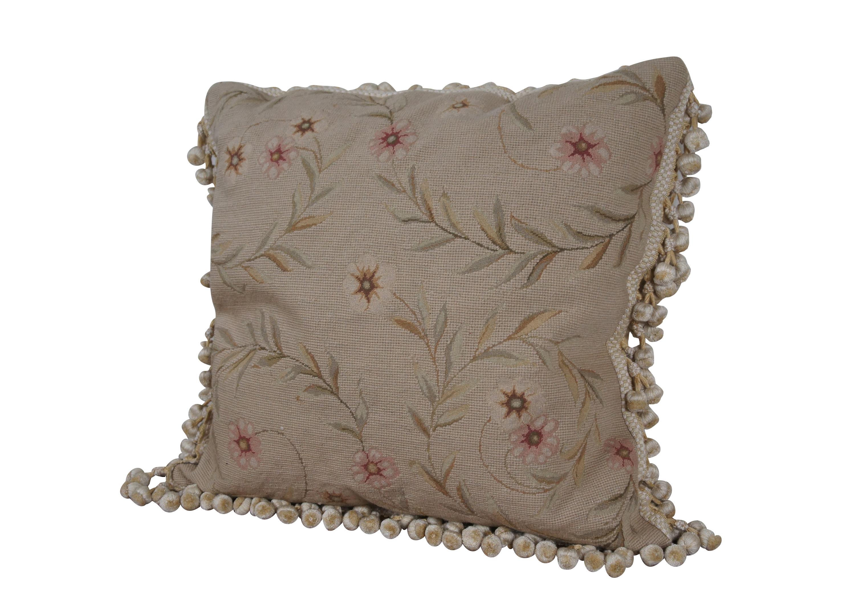 20th century square needlepoint throw pillow, hand embroidered with pink and cream morning glories, on spiraling leafy stems and a beige background. Cream and yellow ball tassel trim. Beige velour back with zipper closure. Down