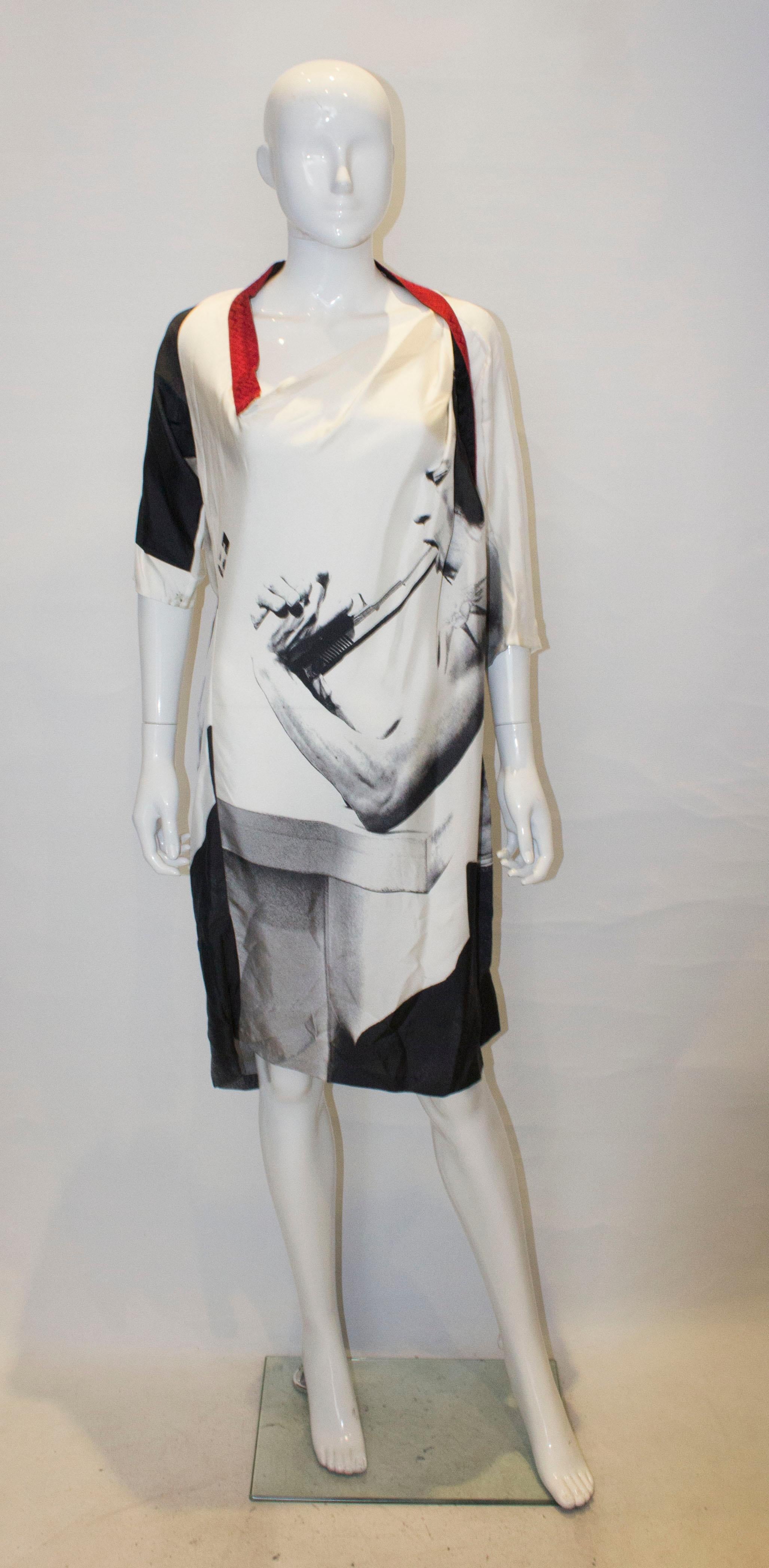 Une robe intéressante du couturier Pagolin. La robe en soie présente une encolure aysmétrique et des plis sur une épaule.  Il présente un imprimé intéressant et des manches courtes. 