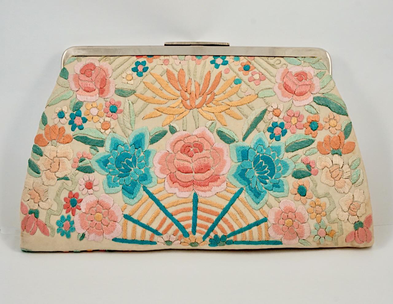 Silk clutch bag with silver tone fittings, and featuring lovely floral embroidery to both sides. Measuring width at the base 22.7 cm / 8.9 inches by height 13.3 cm / 5.2 inches. Inside there is a silk lining with two pockets, and a purse with two