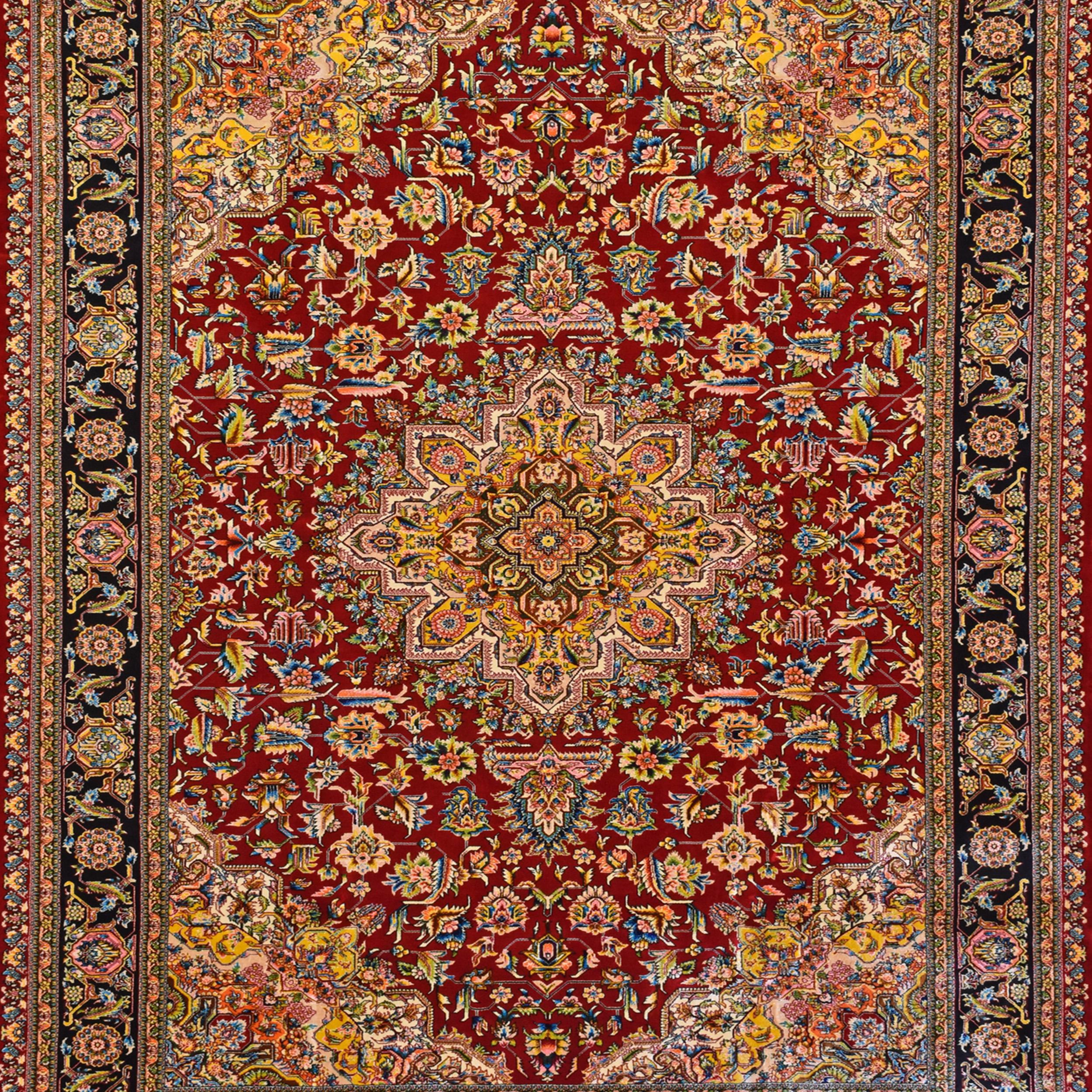 A signed Persian silk carpet woven in the Qajar revival style, echoing the refined medallion layouts of 19th-century Iranian court workshops. The design features a radiating floral medallion centred in a richly ornamented crimson field, flanked by