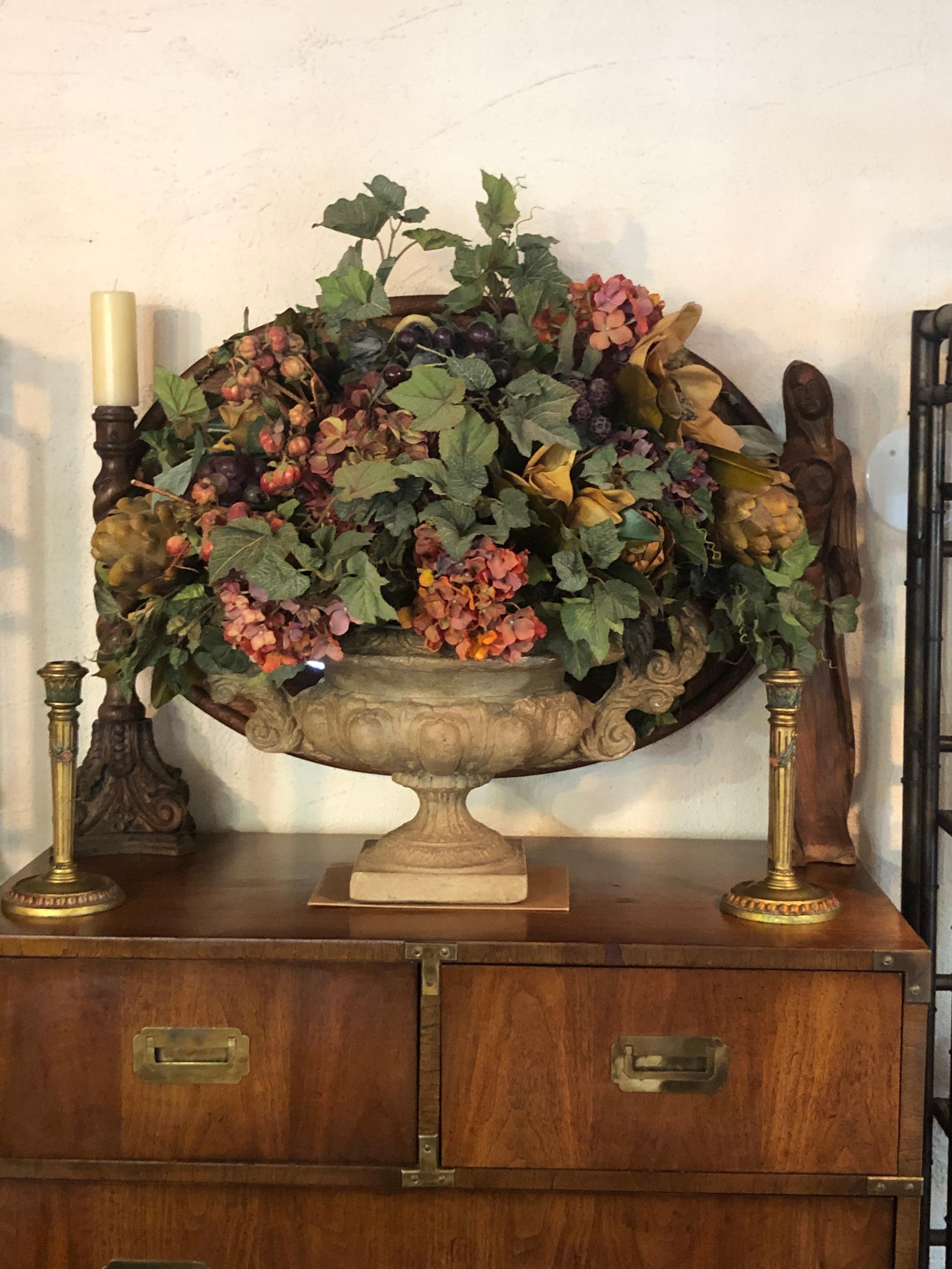 Large Silk flower arrangement in cement Urn. Gorgeous twin handled urn. Solid cast cement or stone. custom made silk floral splay. In excellent condition. Perfect centerpiece for that Holiday table. 
       

