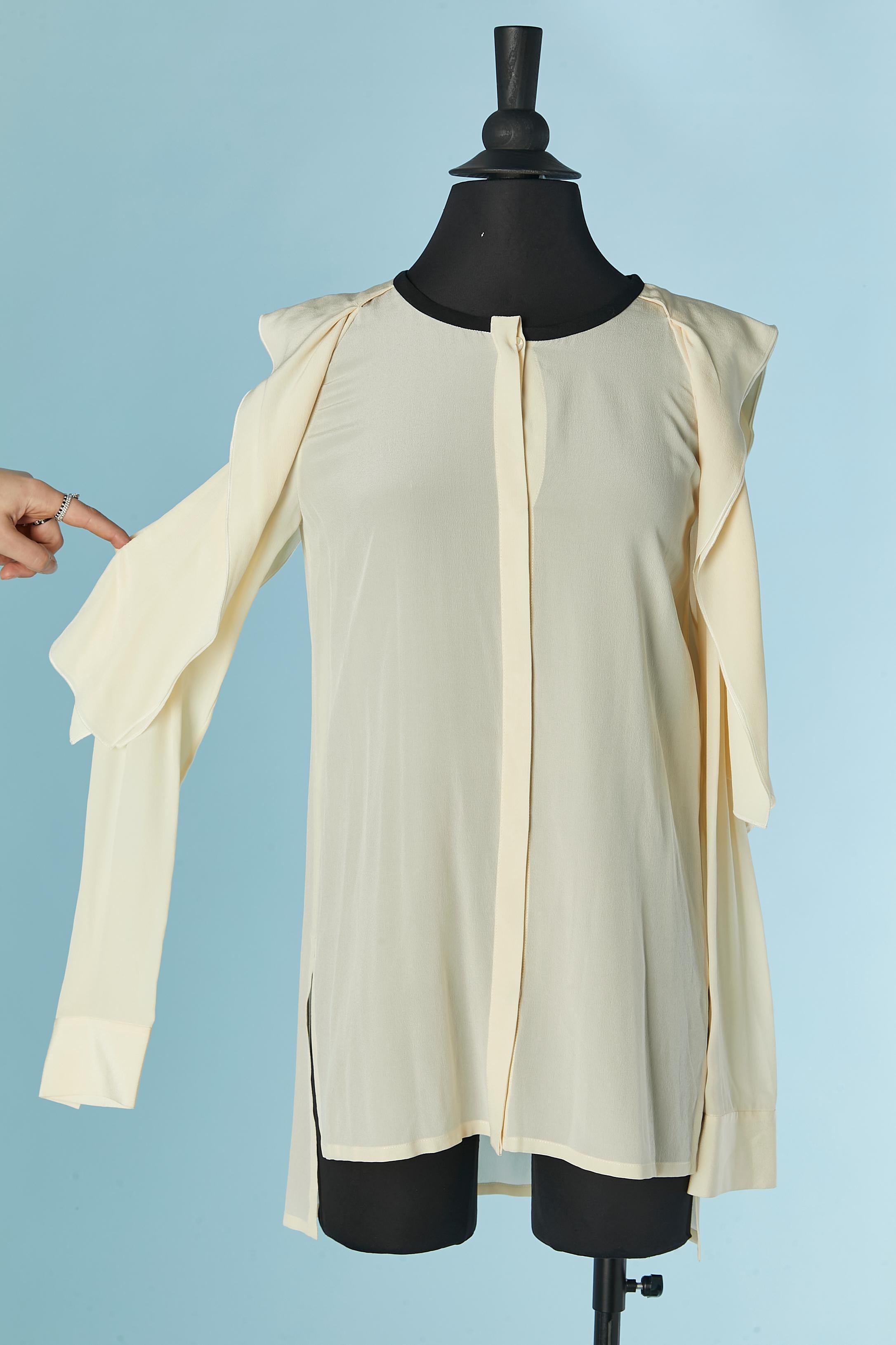 Chemise en soie ivoire ouverte sur l'épaule. Bouton caché et fermeture à la boutonnière sur le milieu du devant. Fendu sur les deux côtés, il est entouré de soie noire.
Neuf avec étiquette.
TAILLE 40 / M-ONE 