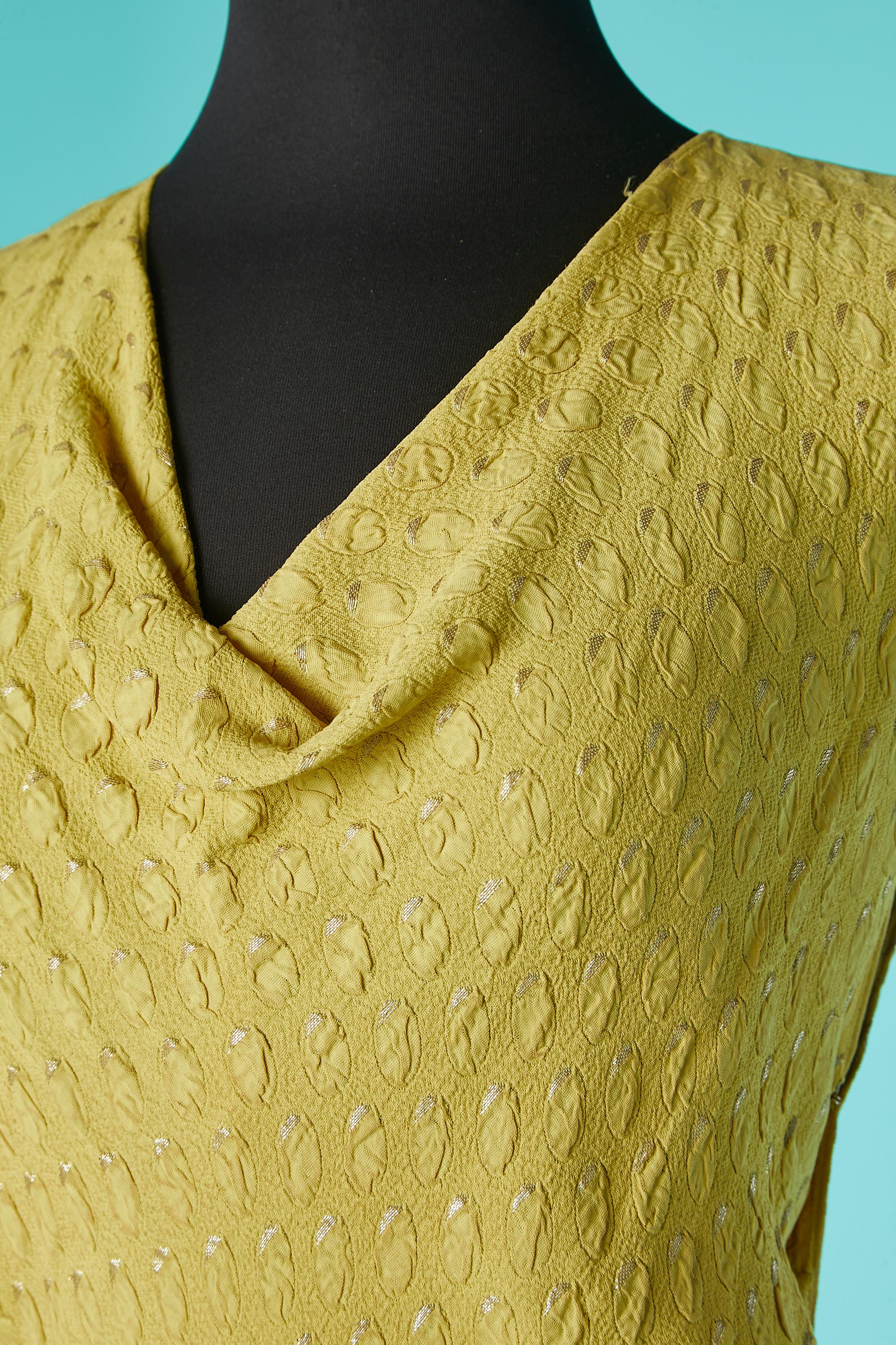 Abendkleid aus gelber Seide und Lurex-Jacquard mit verziertem Gürtel mit kleinen silbernen Lurexkugeln (anscheinend Blaubeeren) als Verzierung. Karabiner und Haken und Öse auf beiden Seiten. 
Oberteil aus Biais, mit 