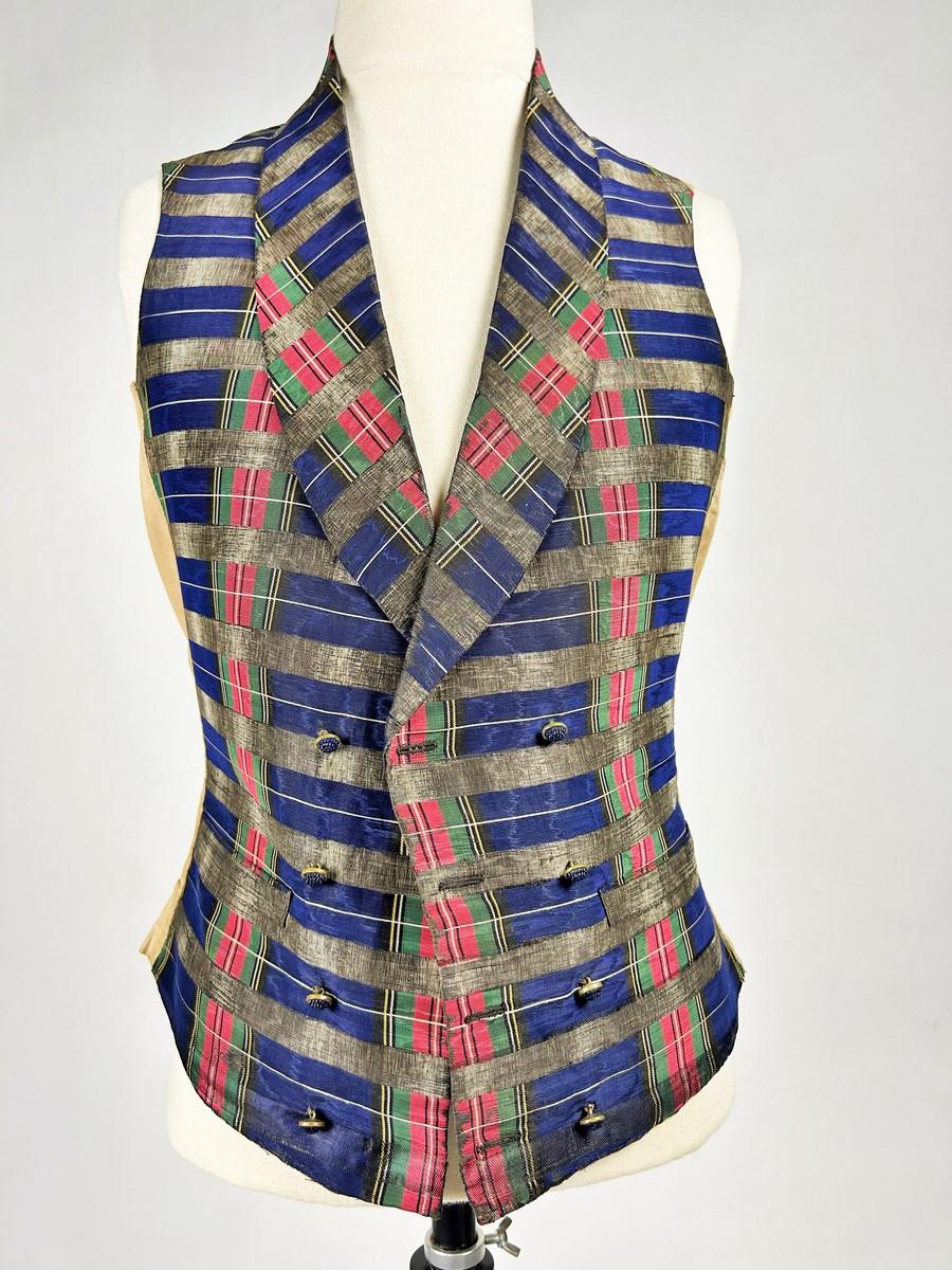 Hacia 1840-1845 Francia
Elegante chaleco encorsetado de tartán de seda de finales del periodo de Louis Philippe. El corte de doble botonadura, el cuello chal que realza el busto y la cintura entallada se ajustan perfectamente a los ideales de los