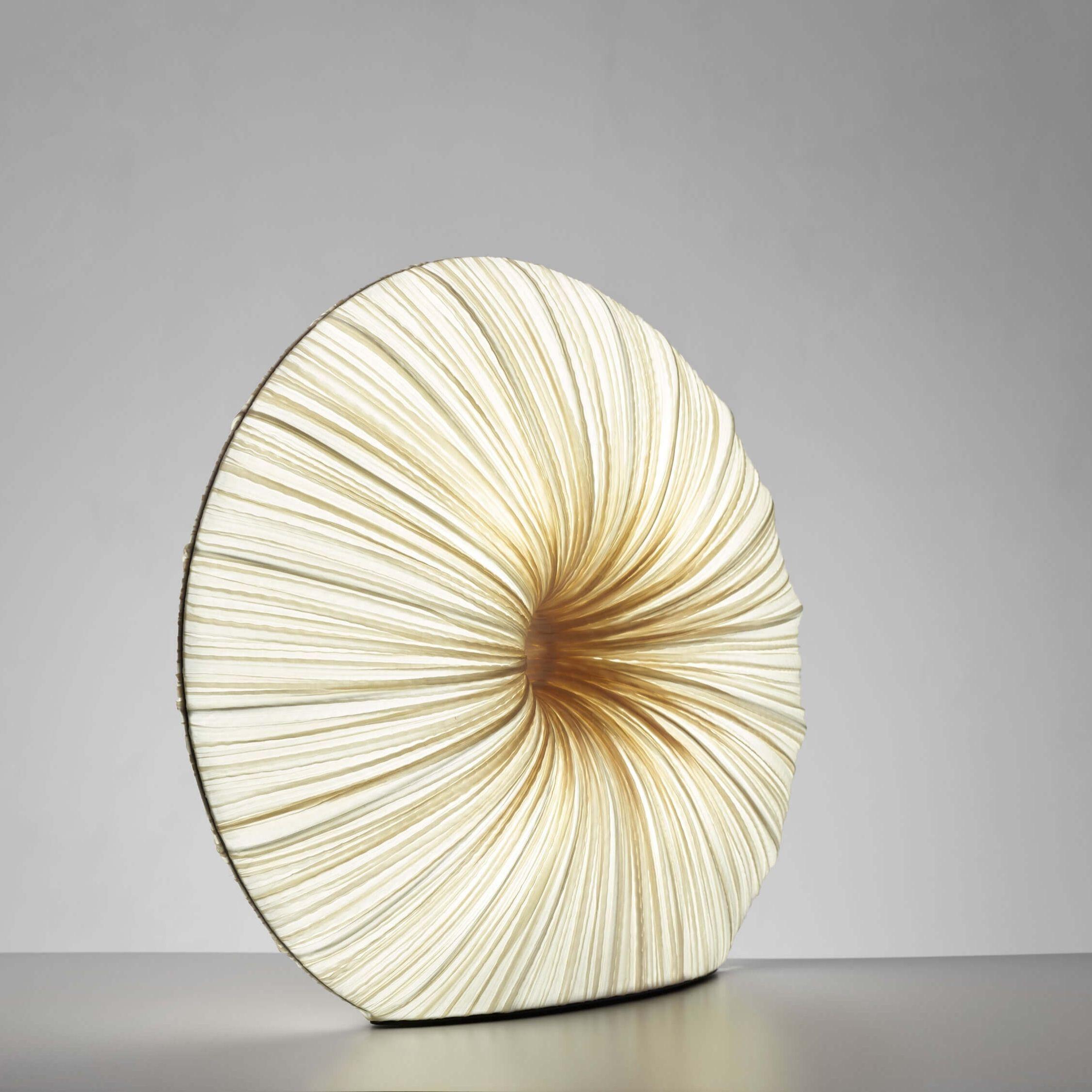Rigua is part of the Orchestra Family, which strikes a chord with its organic, sculptural forms. Taking inspiration from natural musical forms as well as modern sculpture and architecture, Rigua is a table lamp handmade from crushed silk on