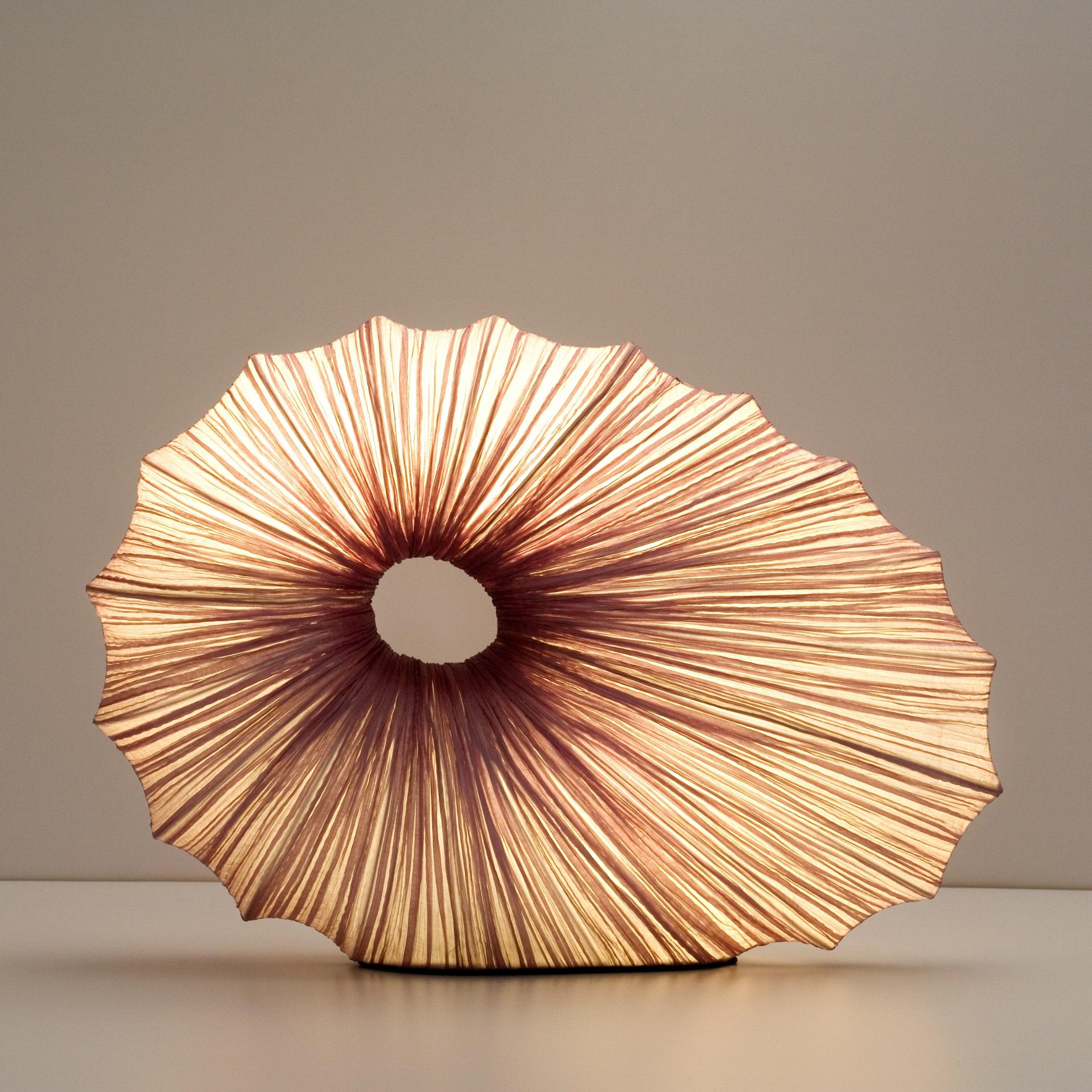 A sculptural silk table lamp that creates a unique and harmonious atmosphere. Hand made of crushed silk on metal.