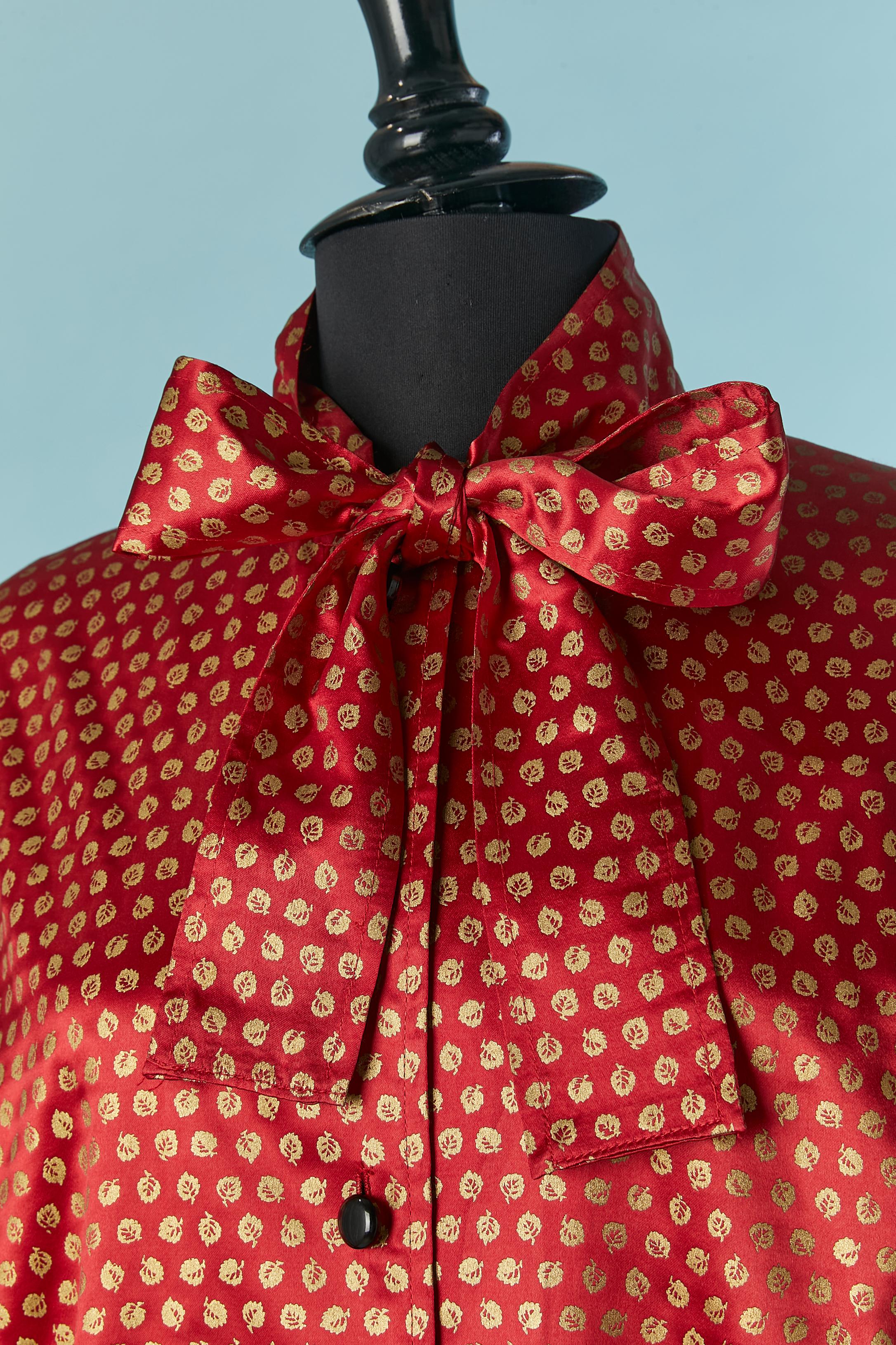 Camicia in raso di seta con motivo a foglie d'oro e papillon. Chiusura con bottoni e asole sul centro del davanti. Zip sui polsini. Maniche raglan. 
TAGLIA M 