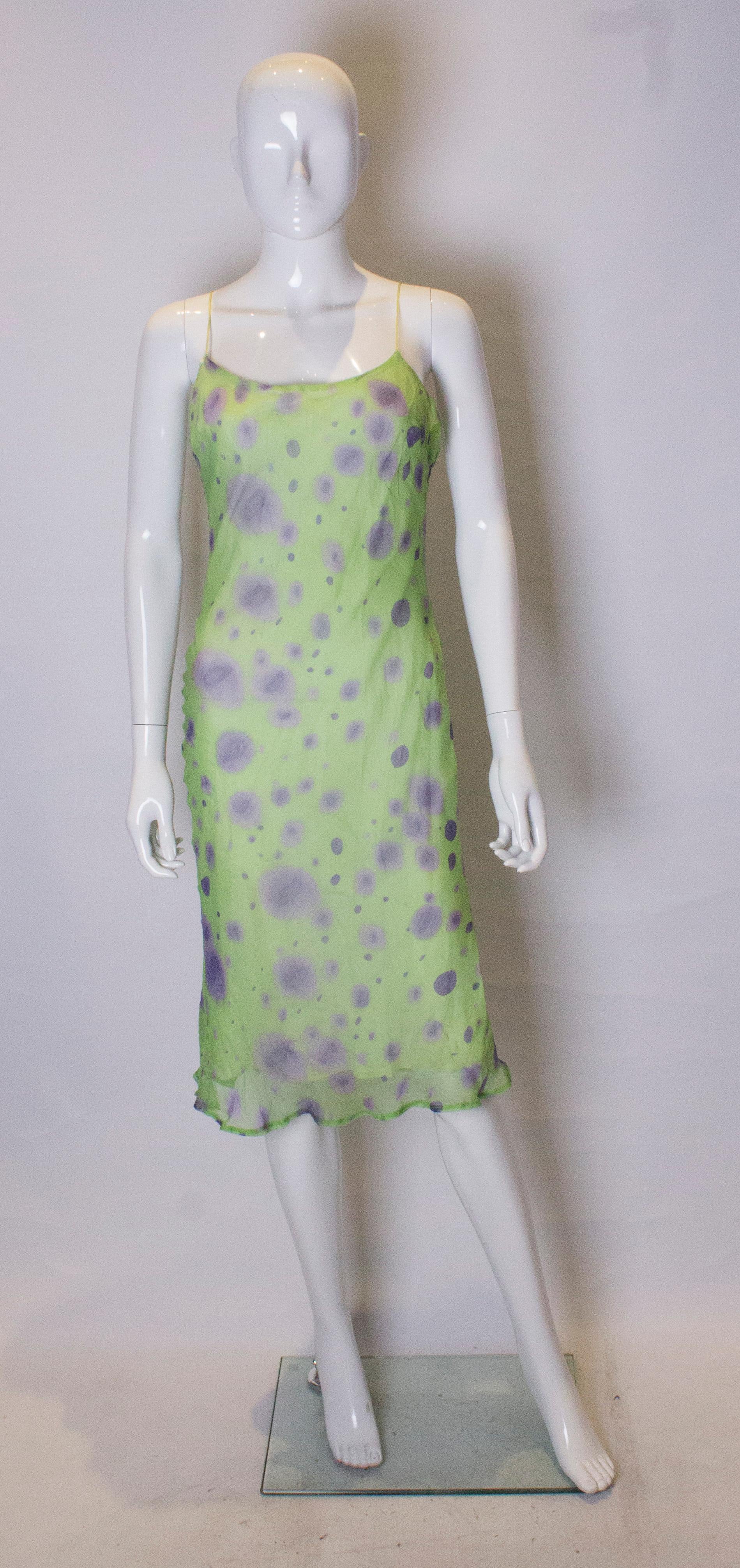 A pretty silk slip dress by Lorena Conti. The dress is made of silk  and has a  pretty green background with a lilac slodge print. The dress is fully lined and has spagetti straps.