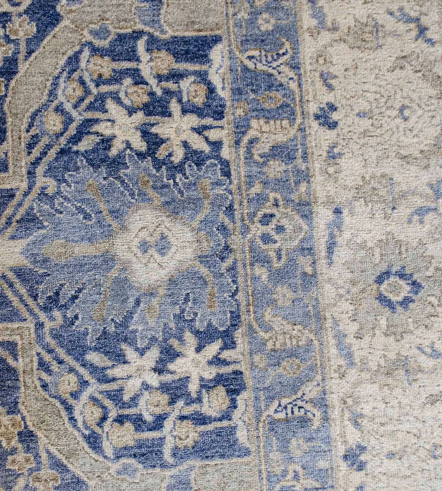 This handwoven silk Persian Tabriz rug has a shaded royal-blue field with and overall design of bold sandy-brown and ivory vine linking palmettes and delicate floral and leafy-vine, in an ivory border of light brown palmette and floral vine between