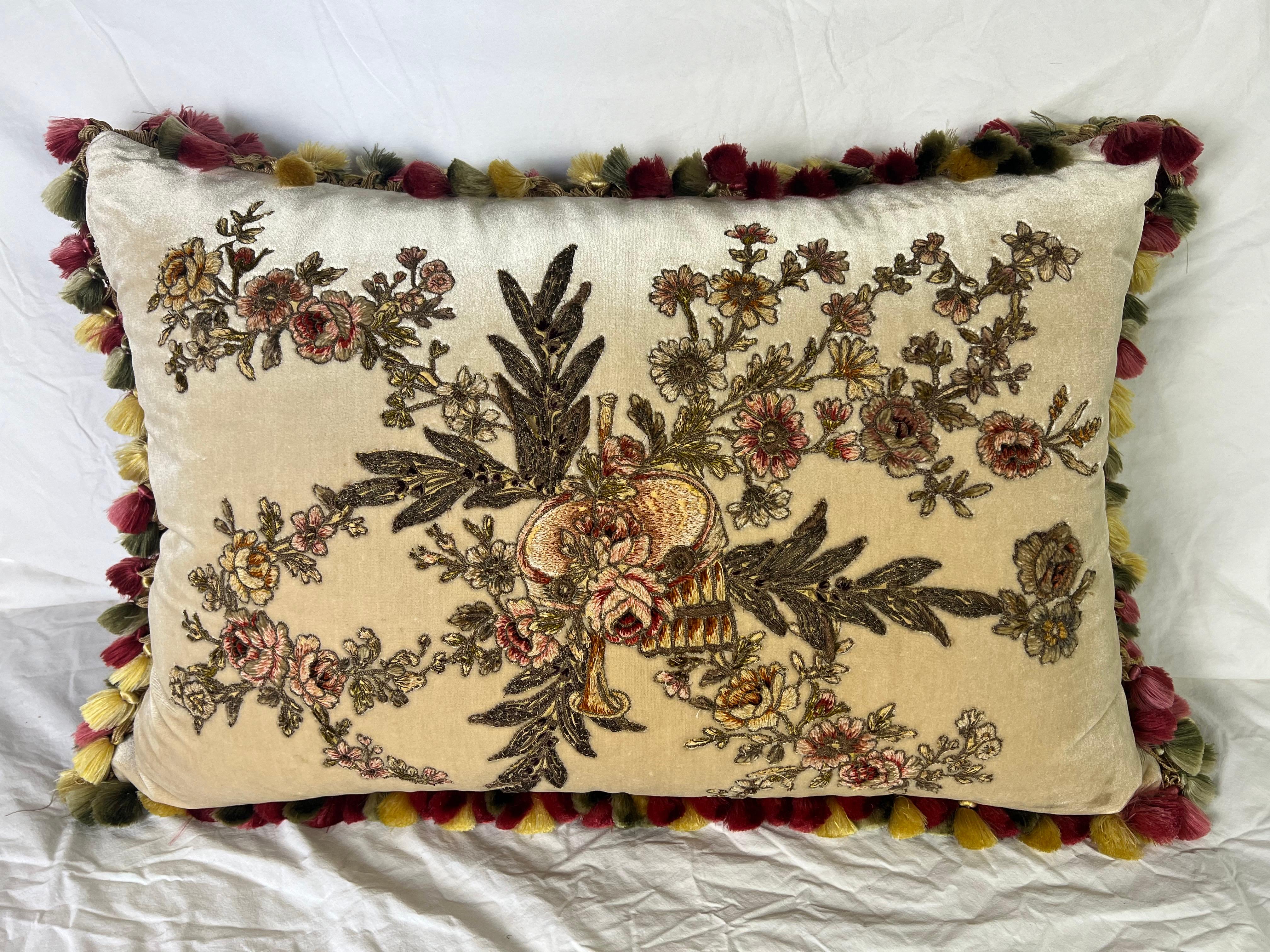Questo lussuoso cuscino da letto è un pezzo decorativo ricco di dettagli realizzato in velluto di seta color crema. Il punto focale è uno squisito ricamo francese del XIX secolo, caratterizzato da una romantica disposizione di motivi floreali e