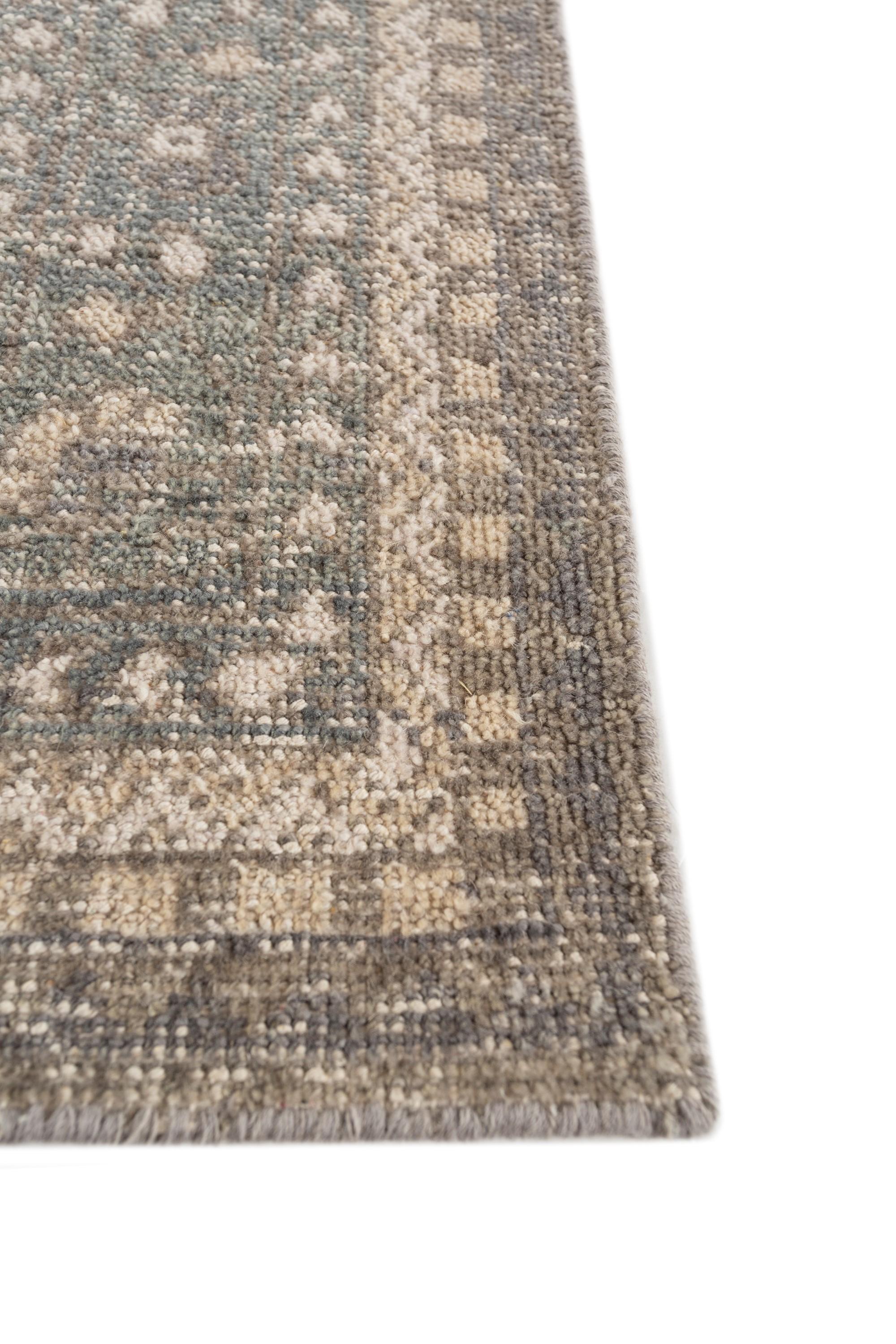 Voici le tapis noué à la main, un chef-d'œuvre fabriqué à partir de laine exquise. Le tapis présente un design captivant avec une couleur de fond ardoise anthracite et une bordure gris moyen sophistiquée. Méticuleusement nouée par des artisans