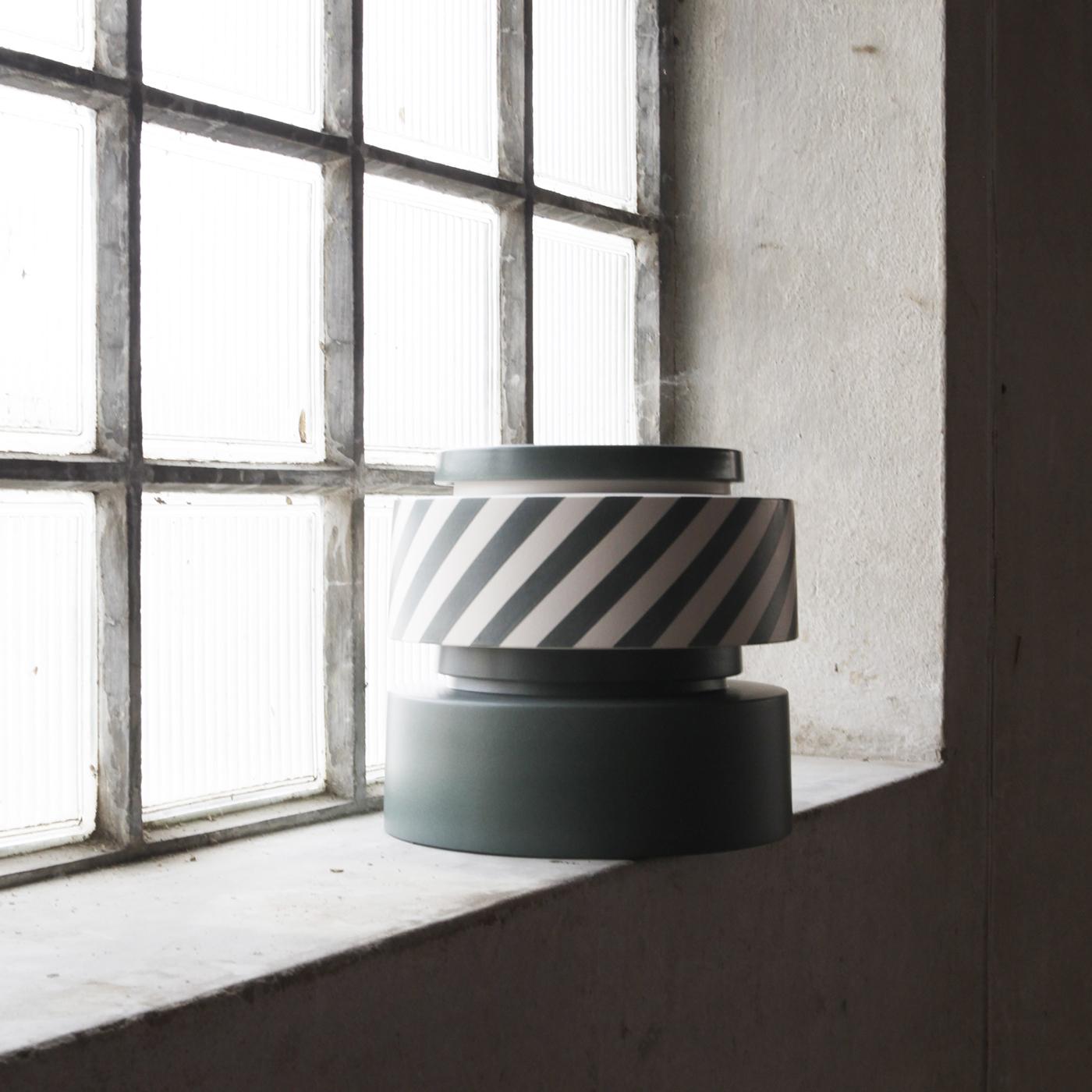 A delightfully stylish ceramic vase where you can keep any precious item, this charming ceramic piece is crafted entirely by hand and comes in matt white with diagonal green stripes. Complete with a ceramic and wood lid, the Silos stackable is a