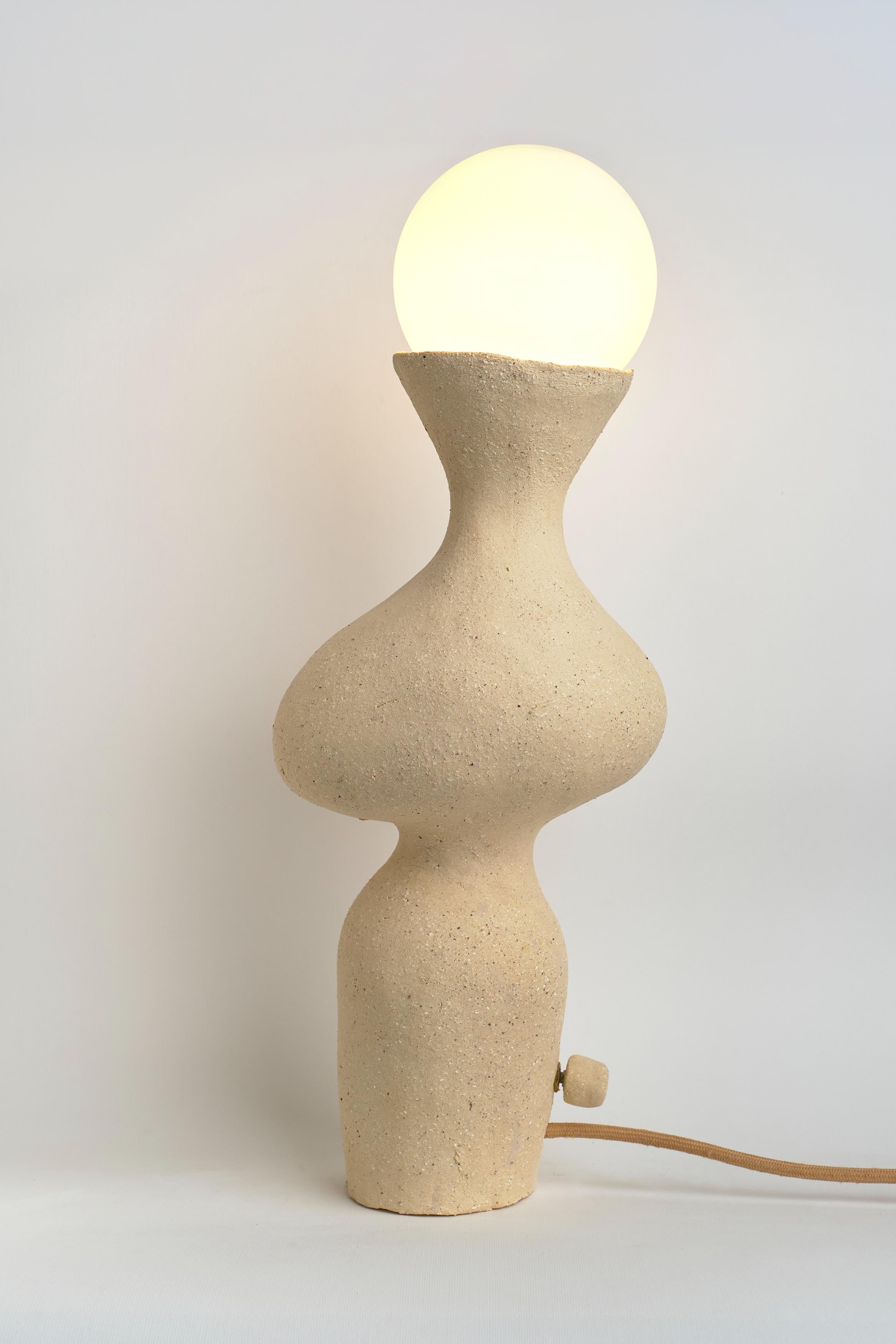 Lampe de table Silueta I de Camila Apaez
Unique en son genre
MATERIAL : Céramique, verre
Dimensions : L 14 x D 19 x H 49 cm

Ila Ceramica est née d'un processus de recherche intérieure où la céramique est devenue un espace de présence, de silence,