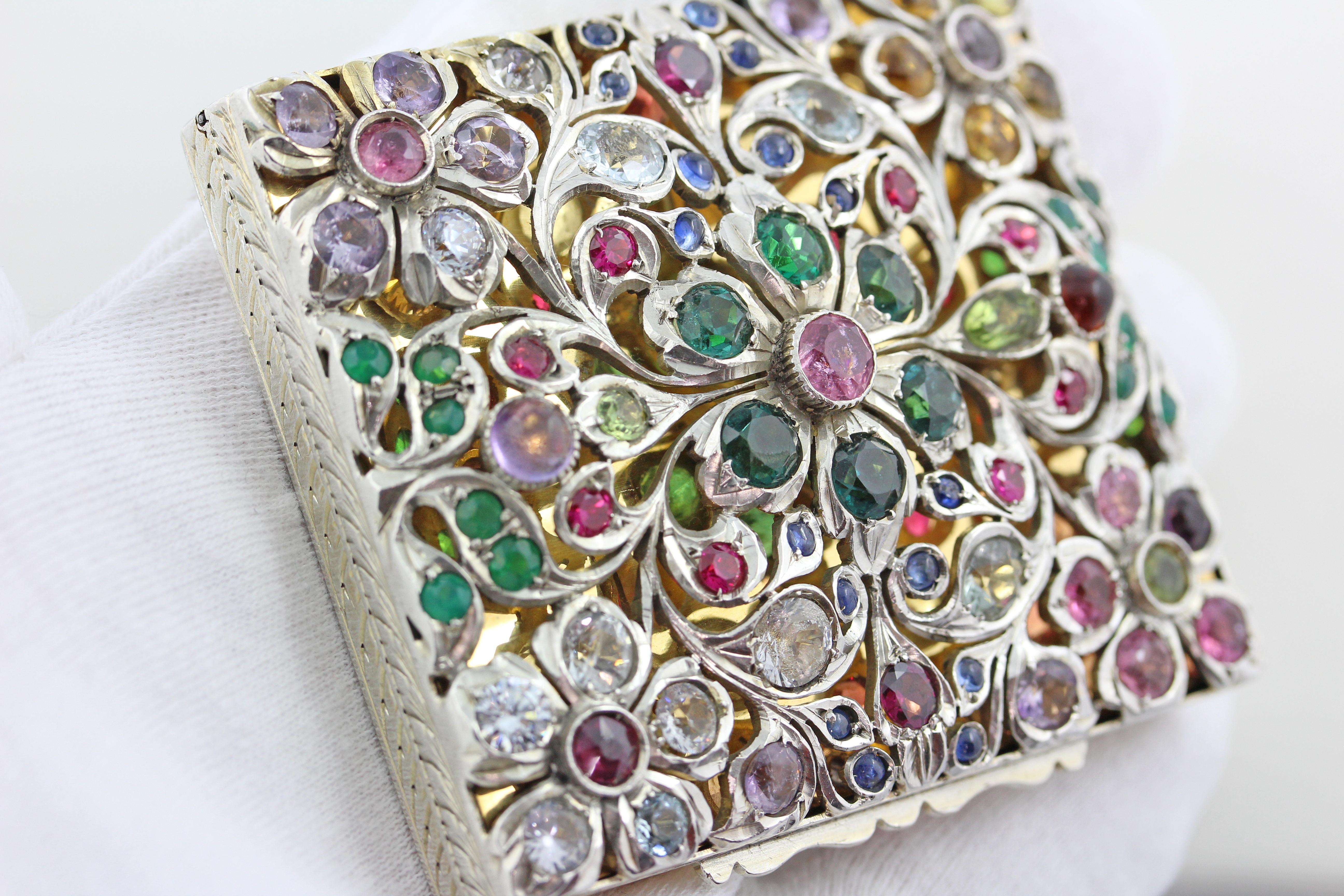 Beautiful box from the late 19th Century completely covered with colorful gems used in the openwork floral patterned cover. 
The interior of the sterling silver box is lined in a 18 Karat gold wash and there is also a mirror. 
Lovely hand engraved