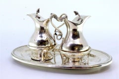 Silver altar cruets with lid knobs on elliptical base with double frieze